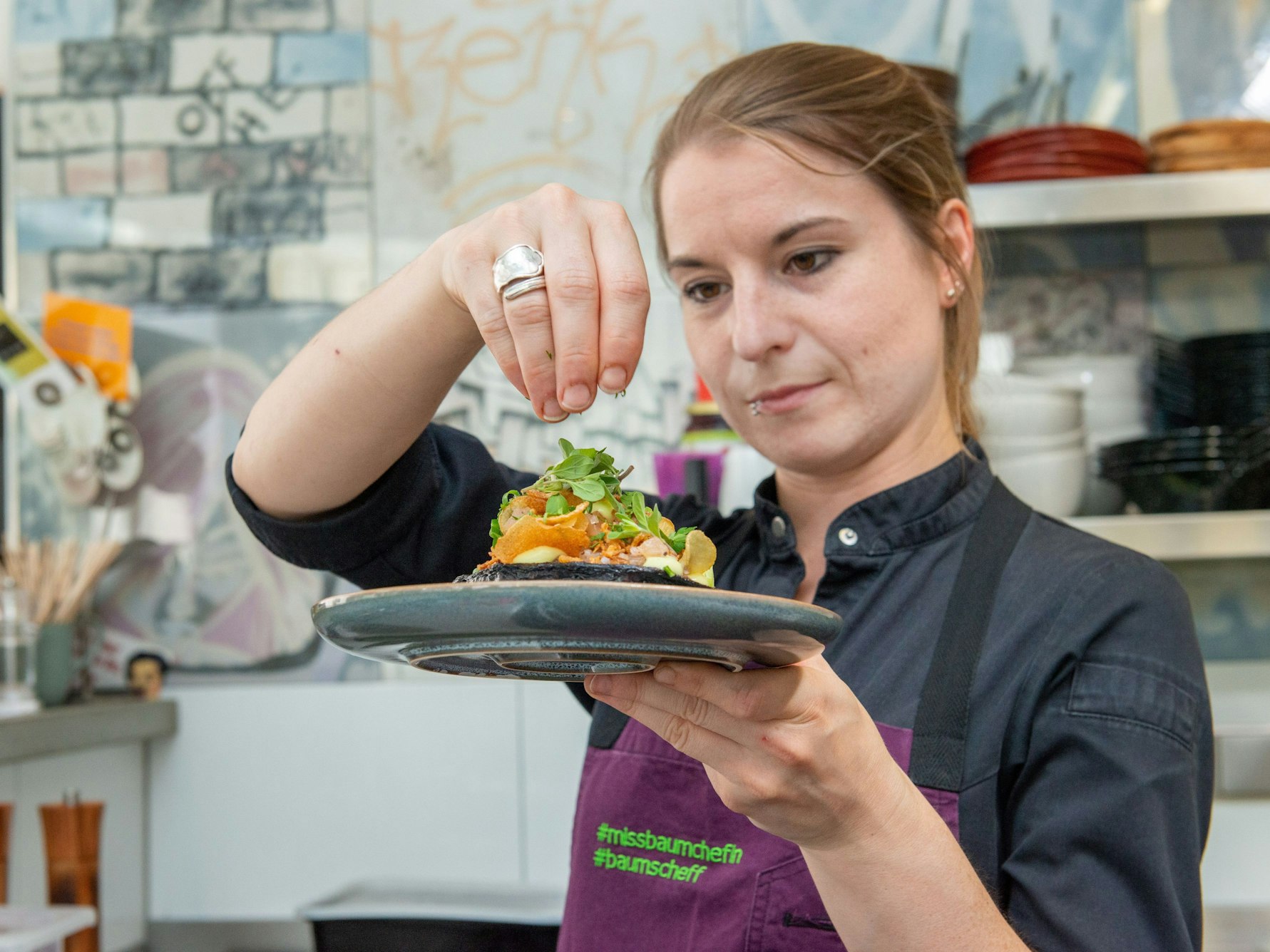 Sonja Baumann vom „Neobiota“ hält einen Teller mit Essen in der Hand.