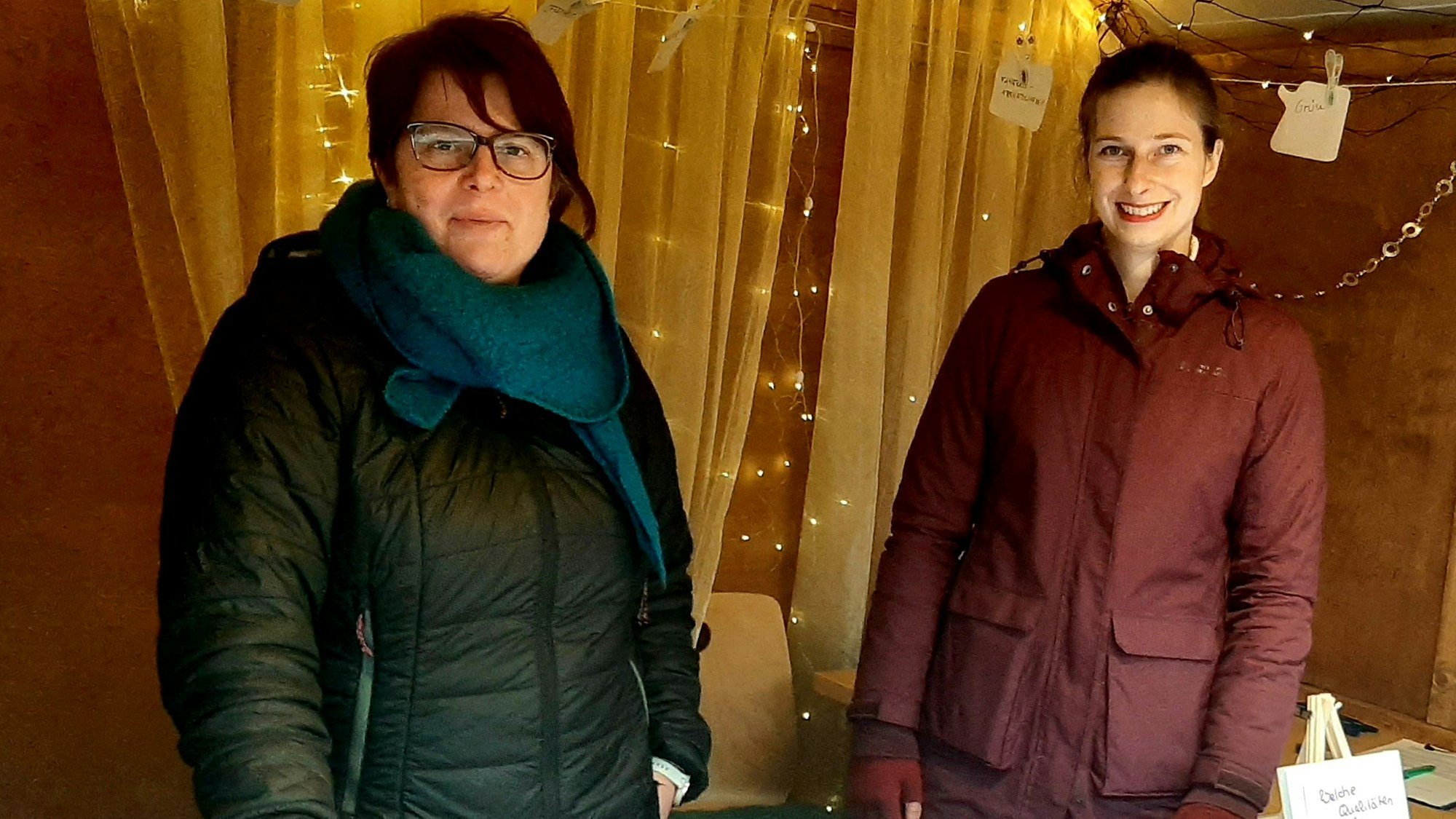 Svenja Stettes (l.) und Stefanie Fabel vom Stadtteilladen Wiesdorf stehen im „Sozialhäuchen“ auf dem Weihnachtsmarkt in der City in Wiesdorf und werben für den zukünftigen Quartierstreff in der alten Feuerwache an der Dönhoffstraße. Leverkusen