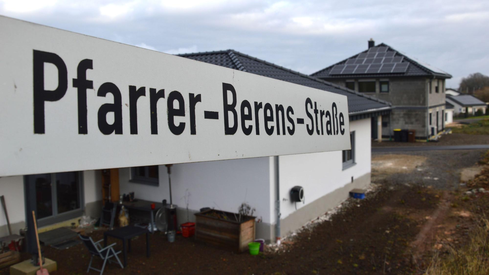 Blick auf ein Straßenschild der Pfarrer-Berens-Straße mit Wohnhäusern im Hintergrund.