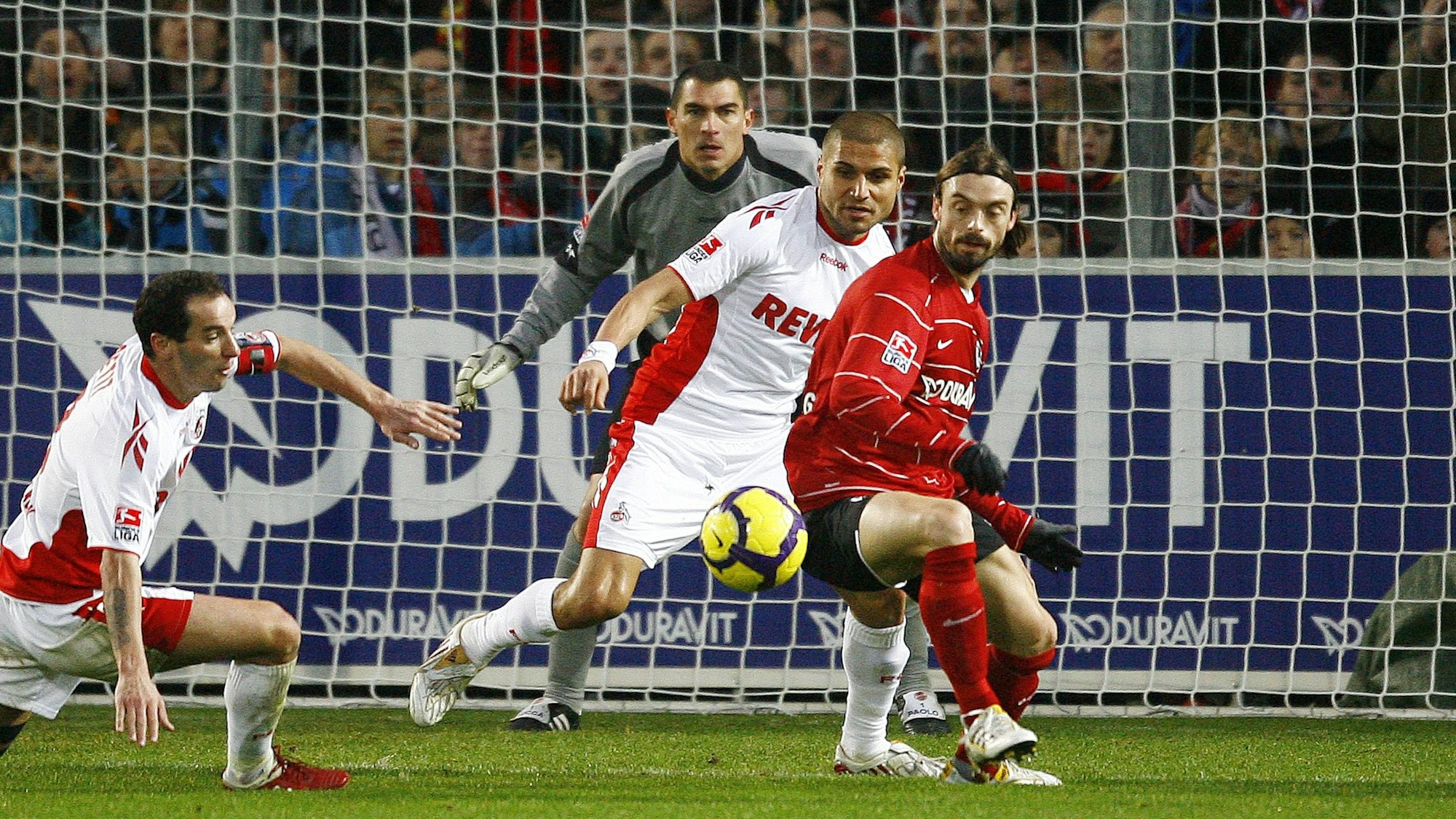 Zwei Verteidiger und der Torwart des 1. FC Köln beobachten im eigenen Strafraum angespannt die Aktion eines Freiburger Stürmers.