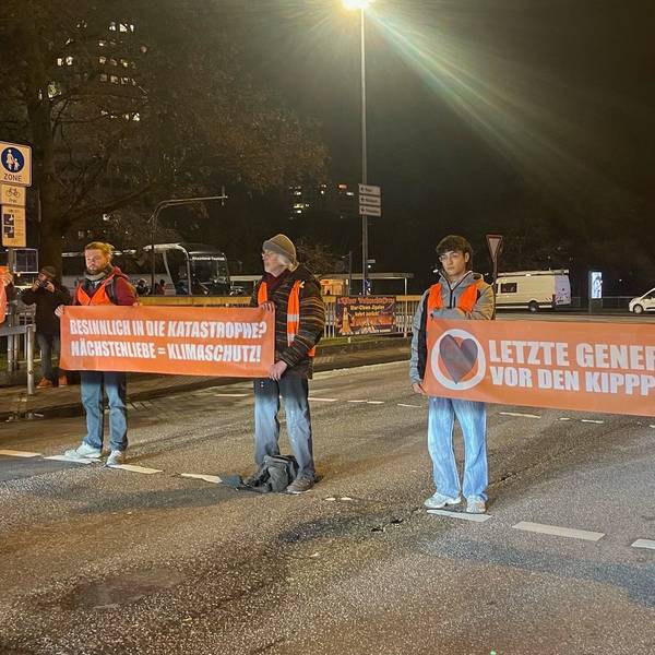 Zu sehen sind fünf Aktivisten der letzten Generation bei einer Straßenblockade.