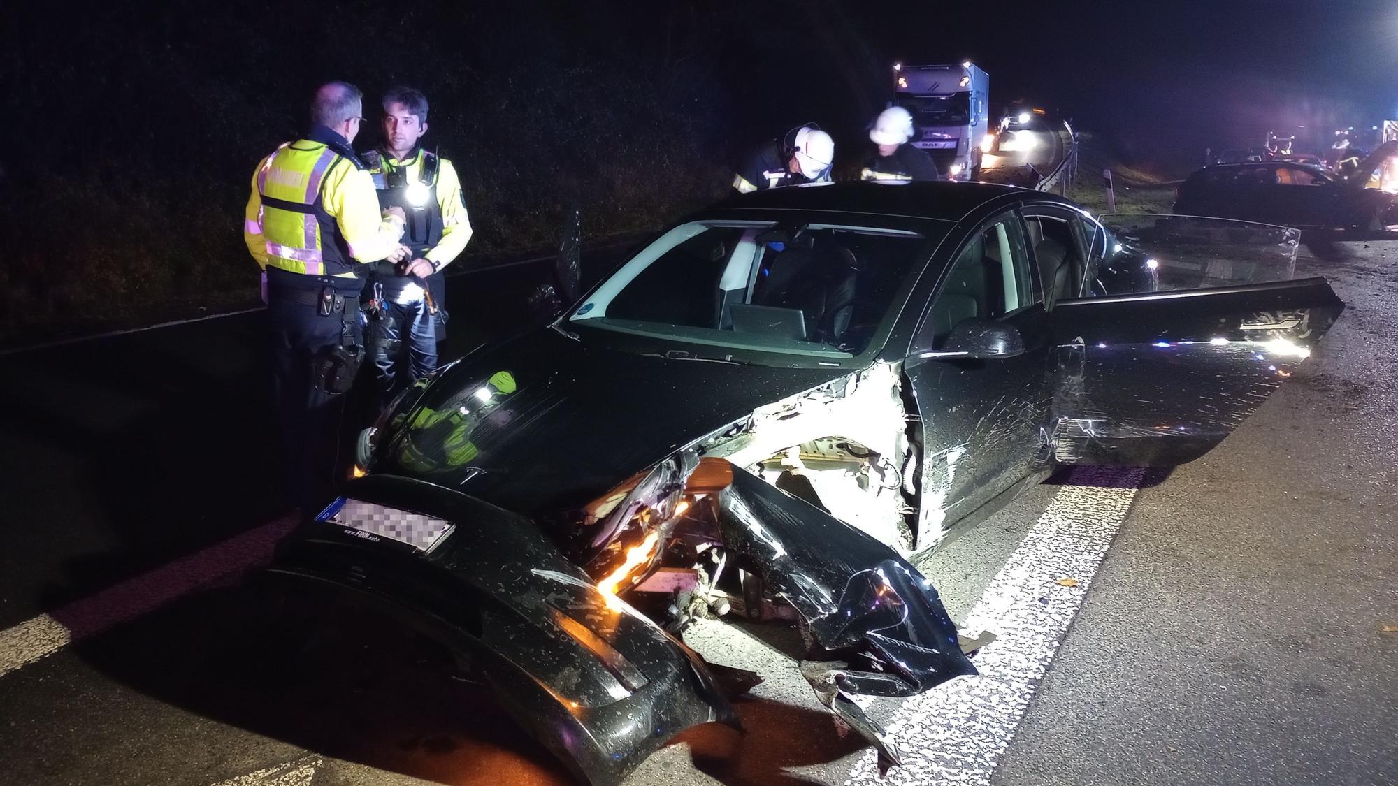 Polizisten und Feuerwehrleute neben einem beschädigten Tesla.