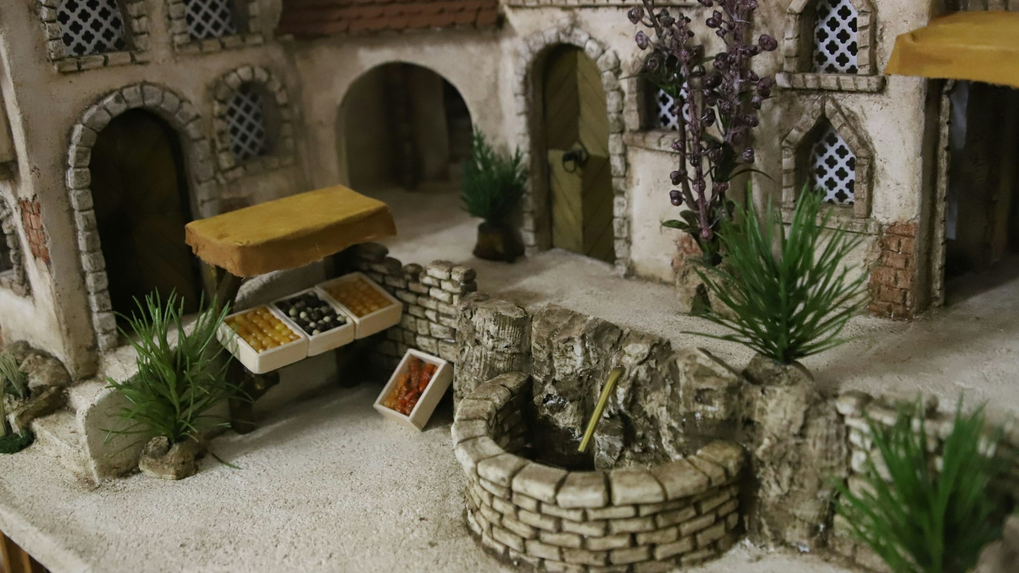 Detail einer Miniatur eines orientalischen Innenhofs mit Brunnen und Obststand.