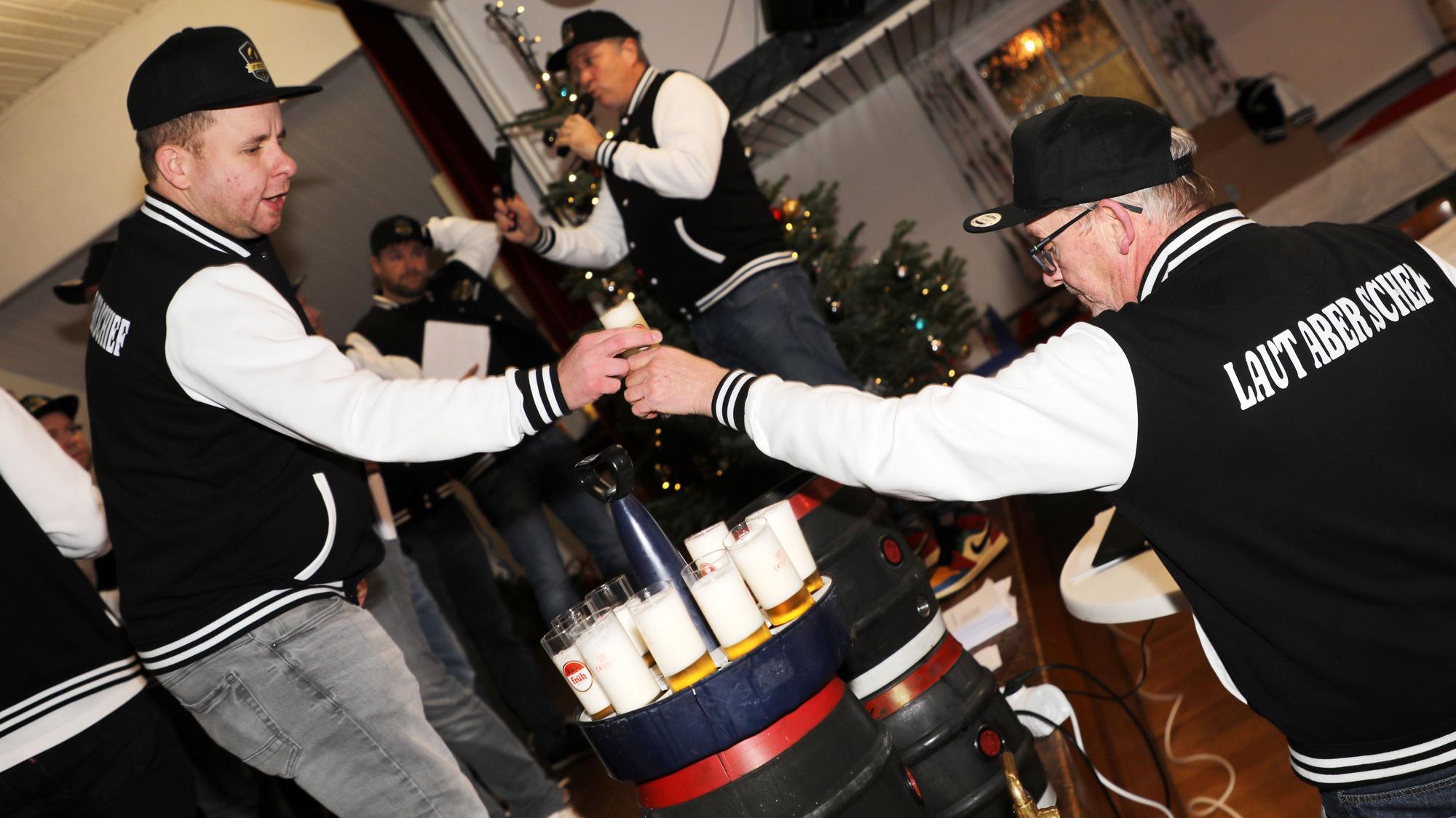 Ein Mann zapft Kölsch und reicht es einem anderen auf die Bühne von Haus Altenrath in Marialinden.