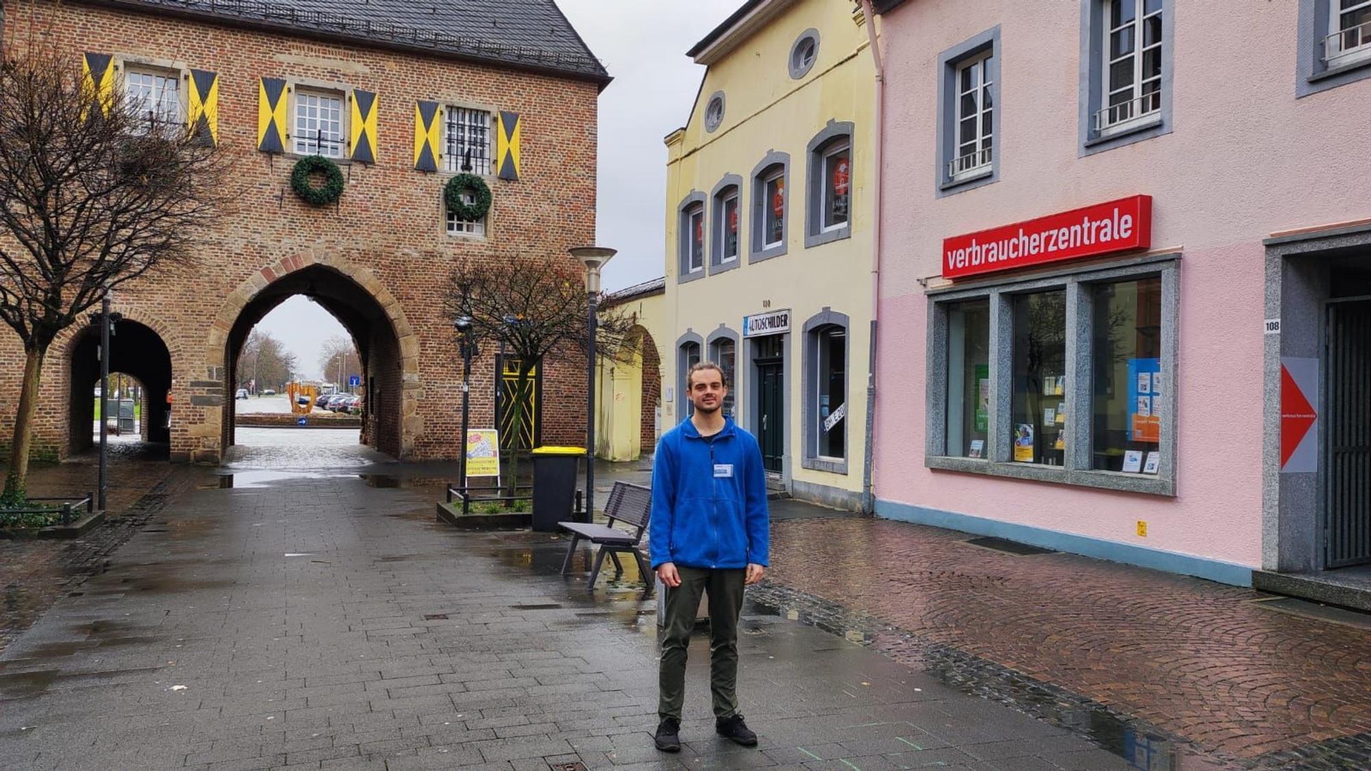 Ein Mann steht in einer Fußgängerzone vor alten Gebäuden.