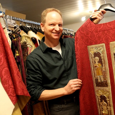 Das Bild zeigt einen Mann, der ein liturgisches Gewand präsentiert.