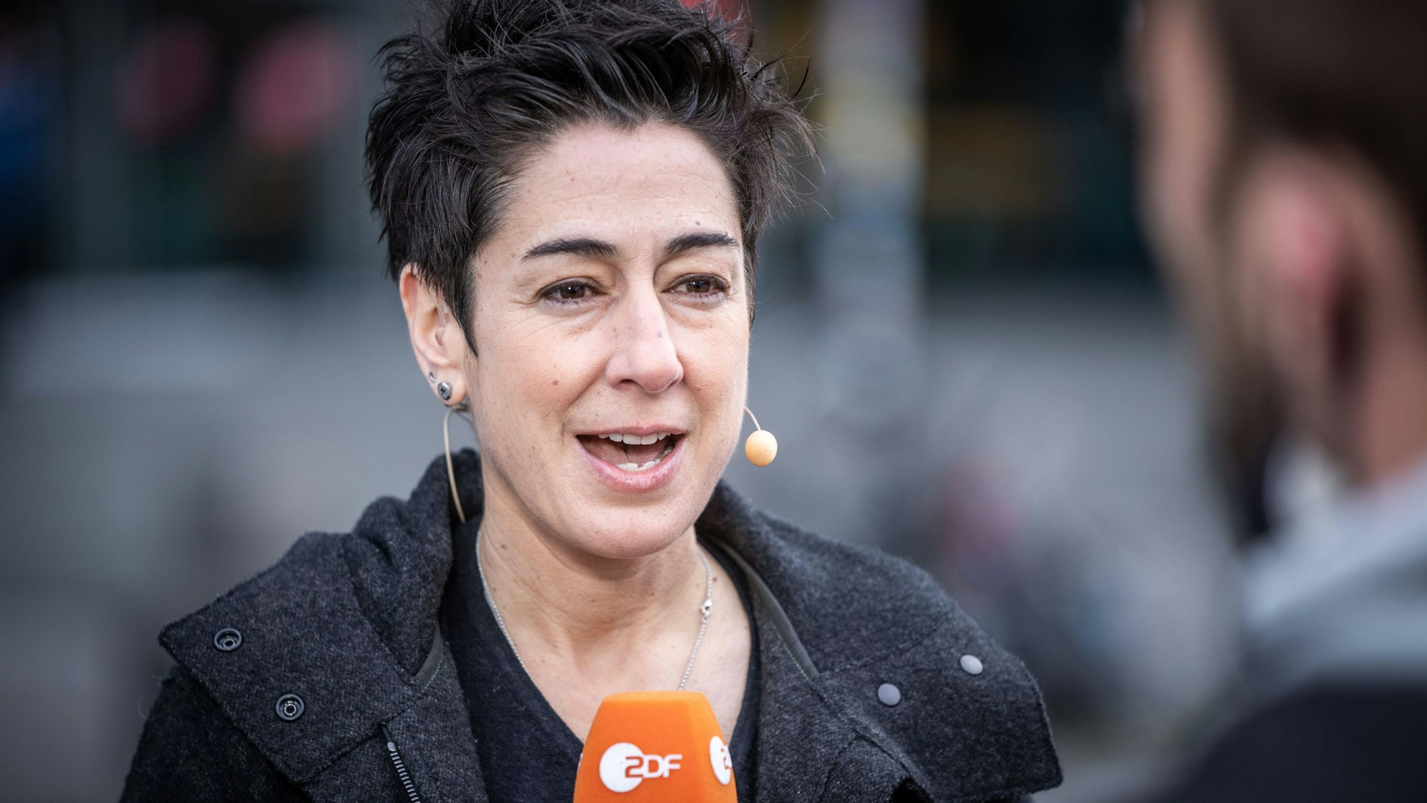 Moderatorin Dunja Hayali steht mit Headset und Mikrofon des Senders ZDF vor einer Kamera und führt ein Interview.