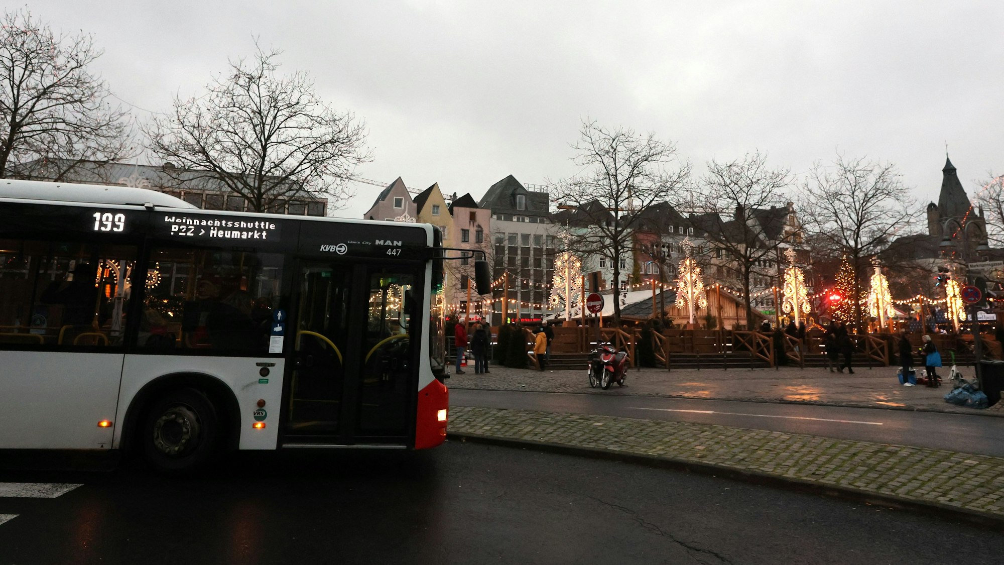 Der Weihnachtsmarkt-Shuttle der KVB fährt Touristen vom Heumarkt zurück zu ihren Reisebussen in Deutz. Im Hintergrund: Warme Lichter vom Kölner Weihnachtsmarkt.