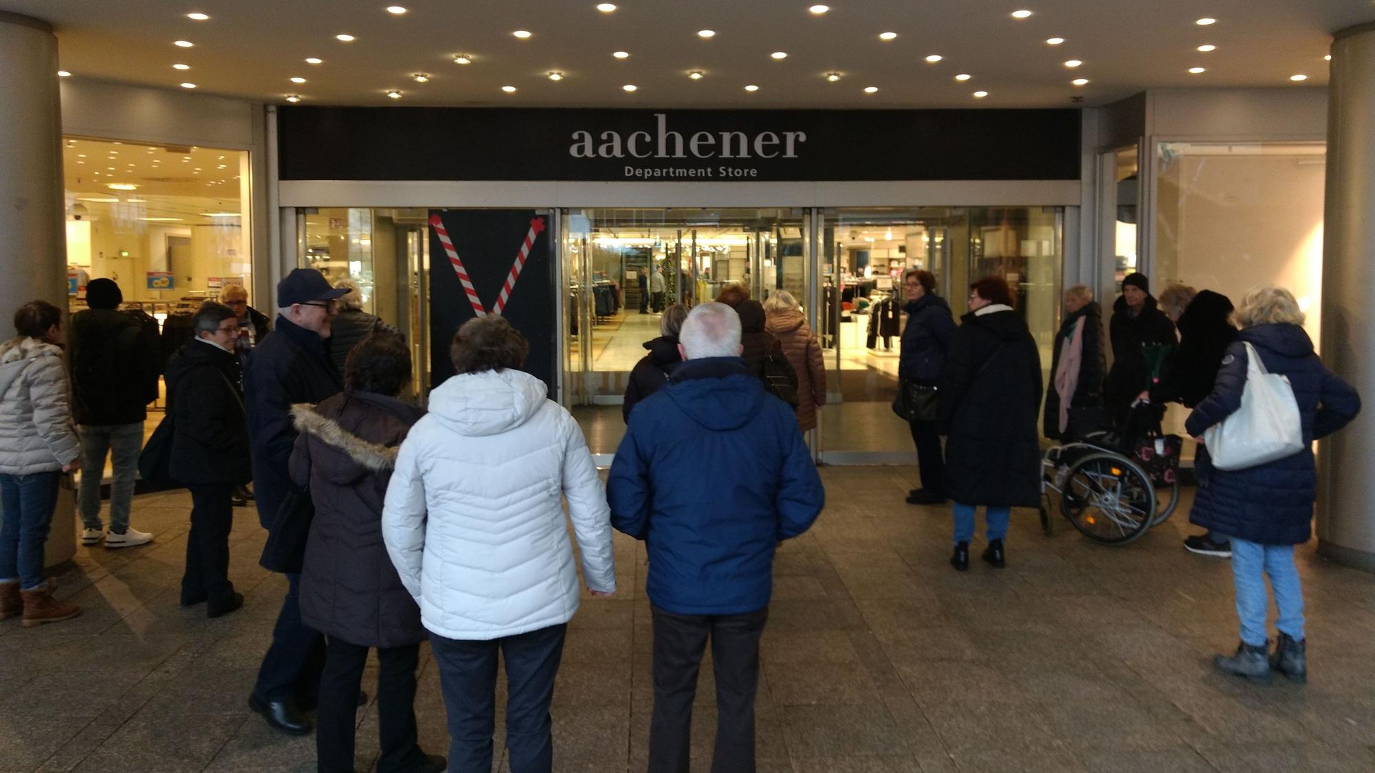 Menschen warten vor einem Modekaufhaus auf Einlass.