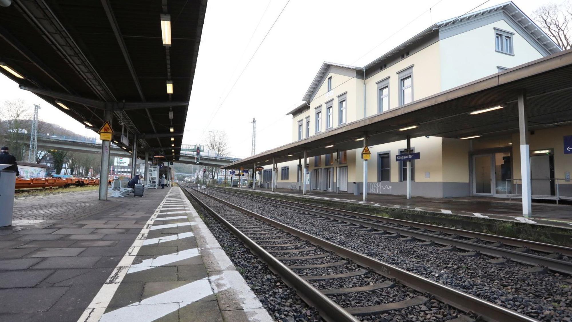 Zwischen einem überdachten Bahnsteig und dem Bahnhofsgebäude verlaufen die Gleise der rechtsrheinischen Bahntrasse.