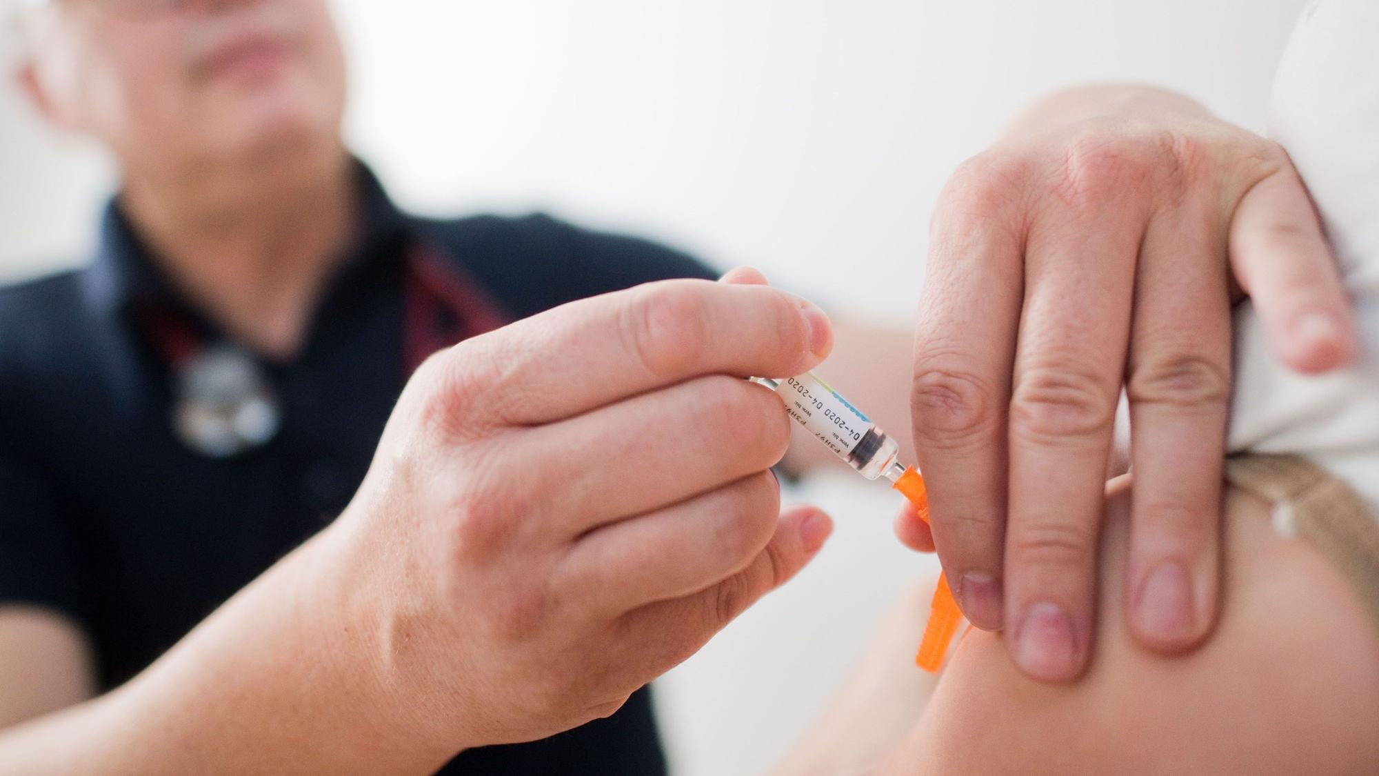 Ein Kinderarzt impft ein Kind mit einem 6-fach-Kombinationsimpfstoff gegen Diphtherie, Tetanus (Wundstarrkrampf), Kinderlähmung (Polio), Keuchhusten (Pertussis), Haemophilus influenzae Typ b (Hib) und Hepatitis B.