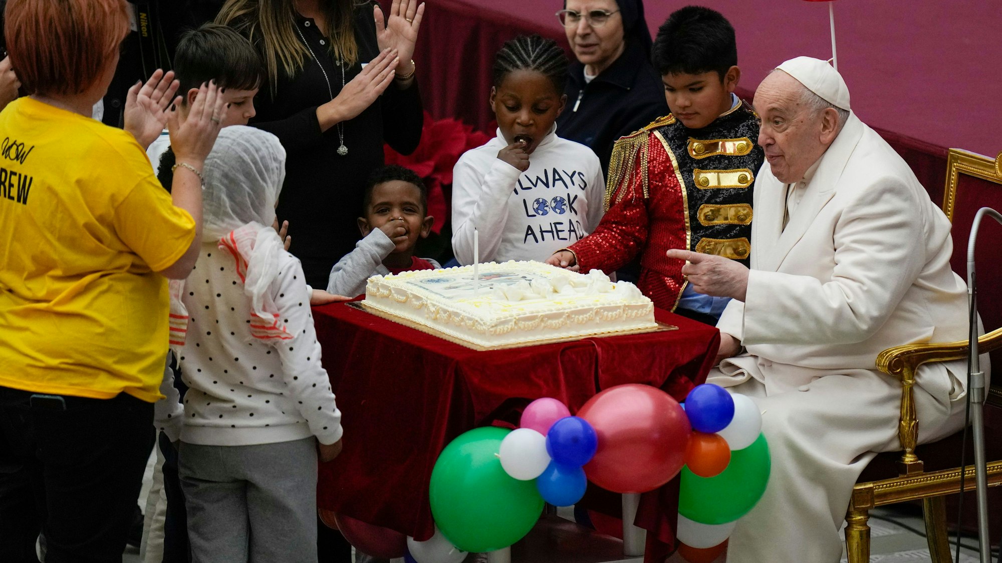 17.12.2023, Vatikan, Vatikanstadt: Papst Franziskus wird ein Kuchen angeboten, während er in der Paul VI.-Halle im Vatikan seinen Geburtstag mit Kindern feiert, die von der Santa Marta Krankenstation unterstützt werden. Papst Franziskus wird am 17. Dezember 87 Jahre alt. Foto: Alessandra Tarantino/AP/dpa +++ dpa-Bildfunk +++
