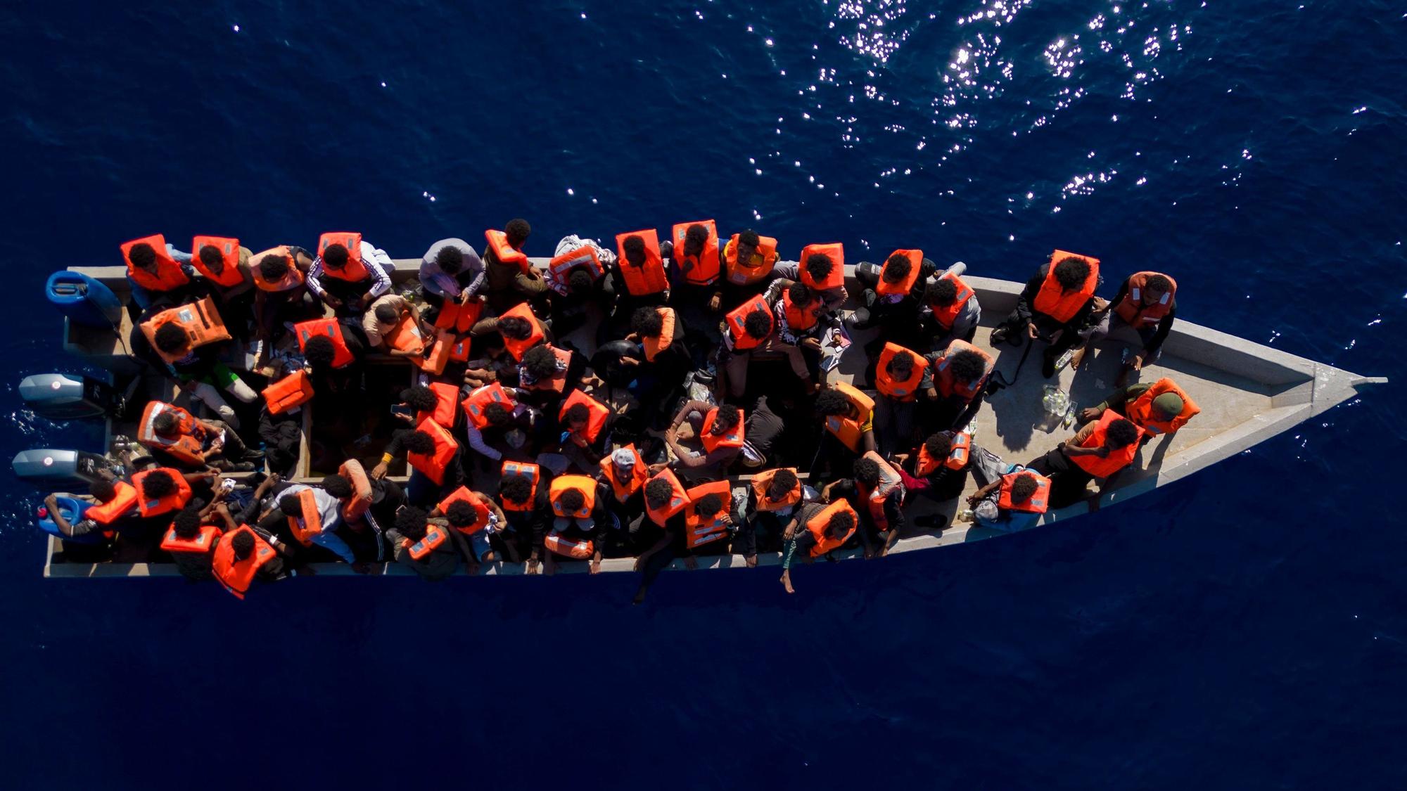 ARCHIV - 17.06.2023, ---: Migranten aus Eritrea, Libyen und dem Sudan sitzen in einem Holzboot, bevor sie von Helfern der spanischen Nichtregierungsorganisation Open Arms im Mittelmeer, etwa 30 Meilen nördlich von Libyen, unterstützt werden. Foto: Joan Mateu Parra/AP/dpa +++ dpa-Bildfunk +++