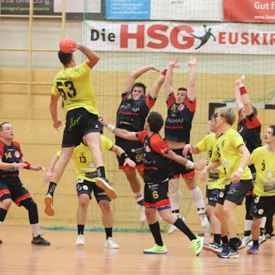 Zwei Palmersheimer Spieler springen hoch, um einen Torwurf abzuwehren.Rund um sie herum stehen Mitspieler und Gegner.