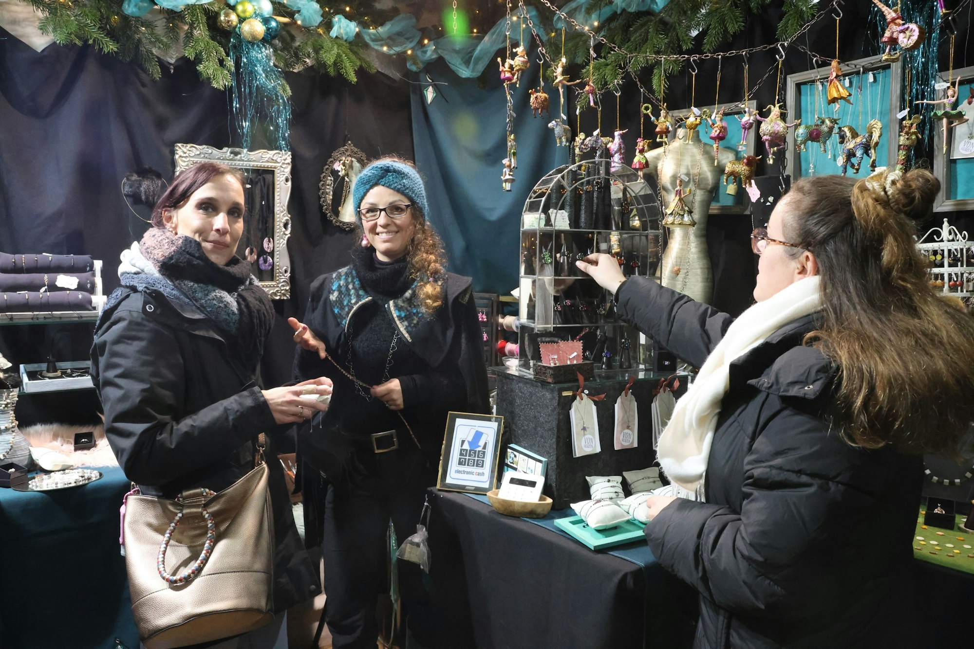 Jenny Giesen-Ufer (links) und Fiona Suck lassen sich bei Janina Ziemann (Mitte) auf dem Christkindmarkt in Engelskirchen Schmuck zeigen.