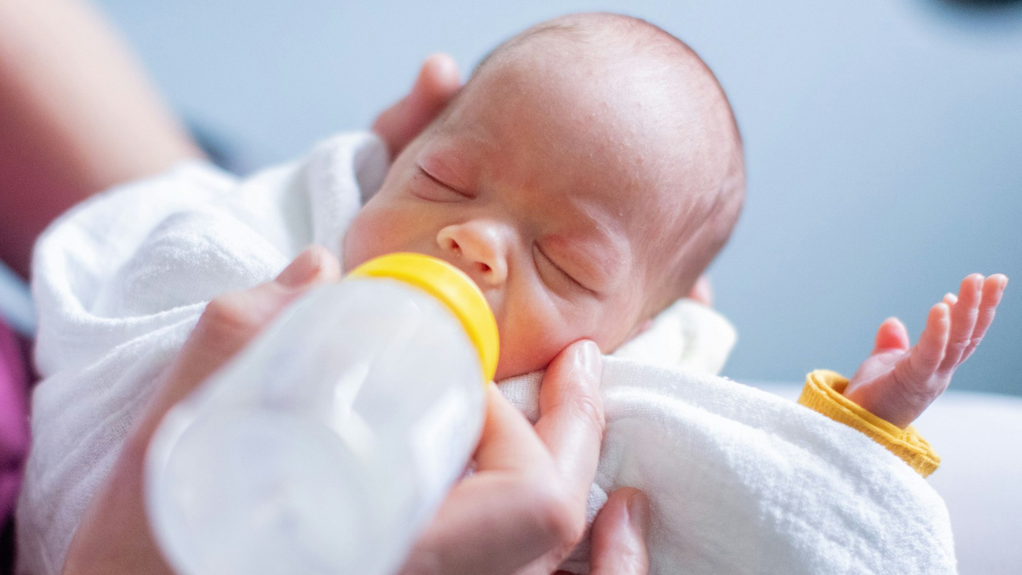 Ein Frühchen trinkt Milch aus der Flasche.