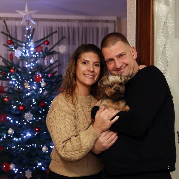 Daniela und Thomas Marschalleck mit ihrem kleinen Hund auf dem Arm vor dem Weihnachtsbaum