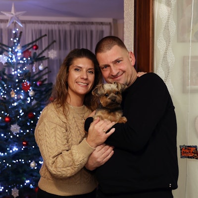 Daniela und Thomas Marschalleck mit ihrem kleinen Hund auf dem Arm vor dem Weihnachtsbaum