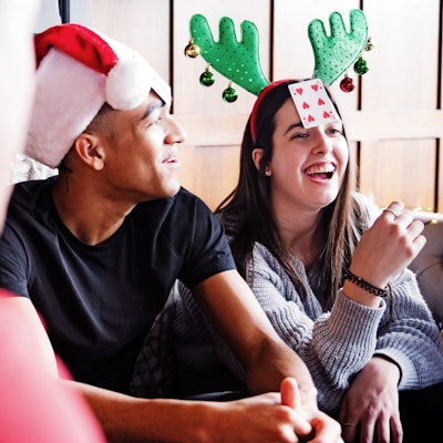 Eine Gruppe junger Leute spielt an Weihnachten ein Kartenspiel.