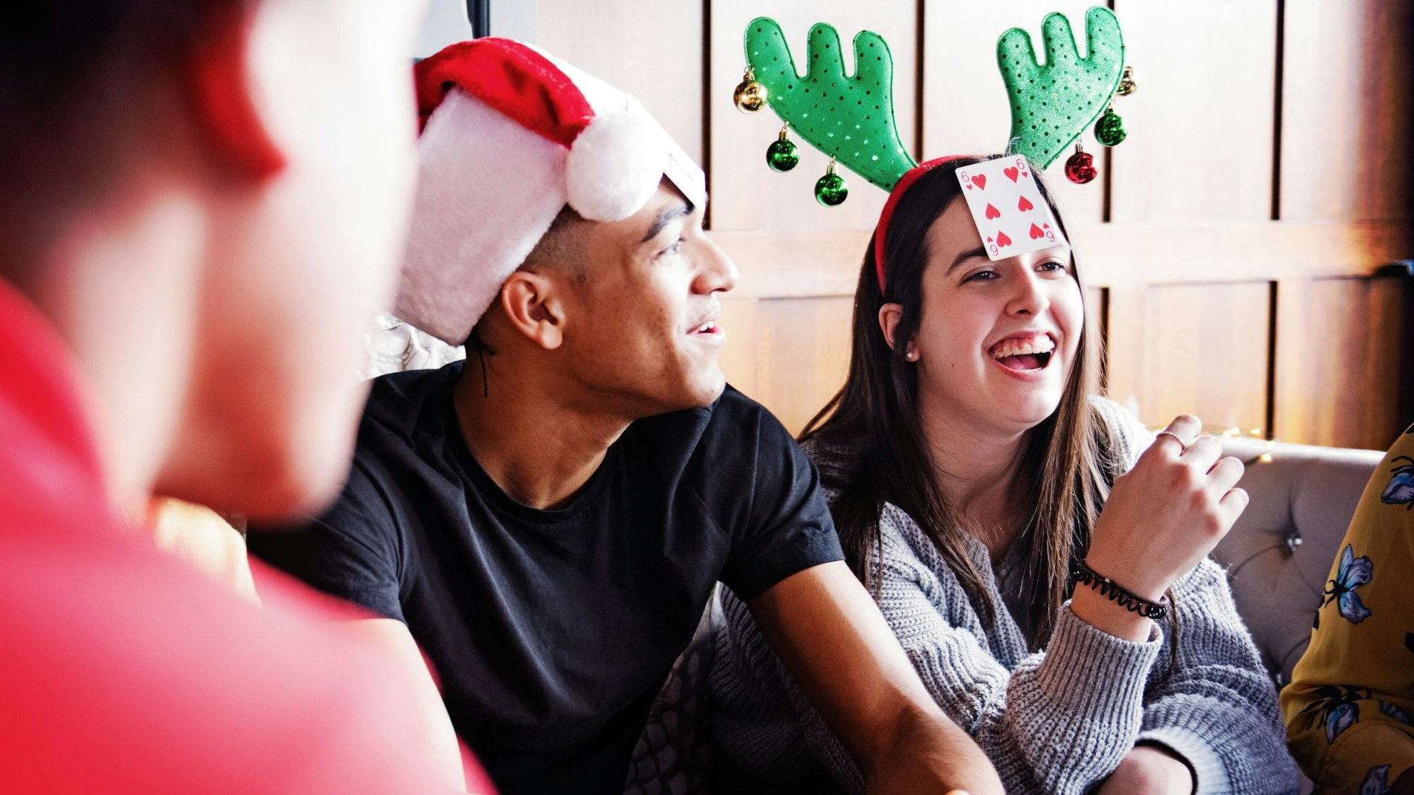 Eine Gruppe junger Leute spielt an Weihnachten ein Kartenspiel.