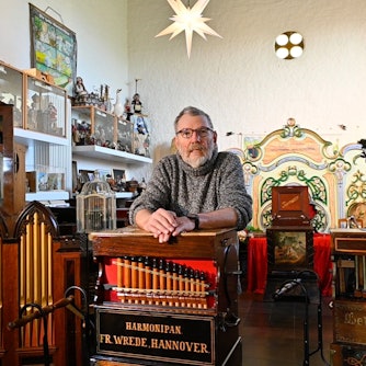 Ein Mann lehnt an einer Drehorgel.