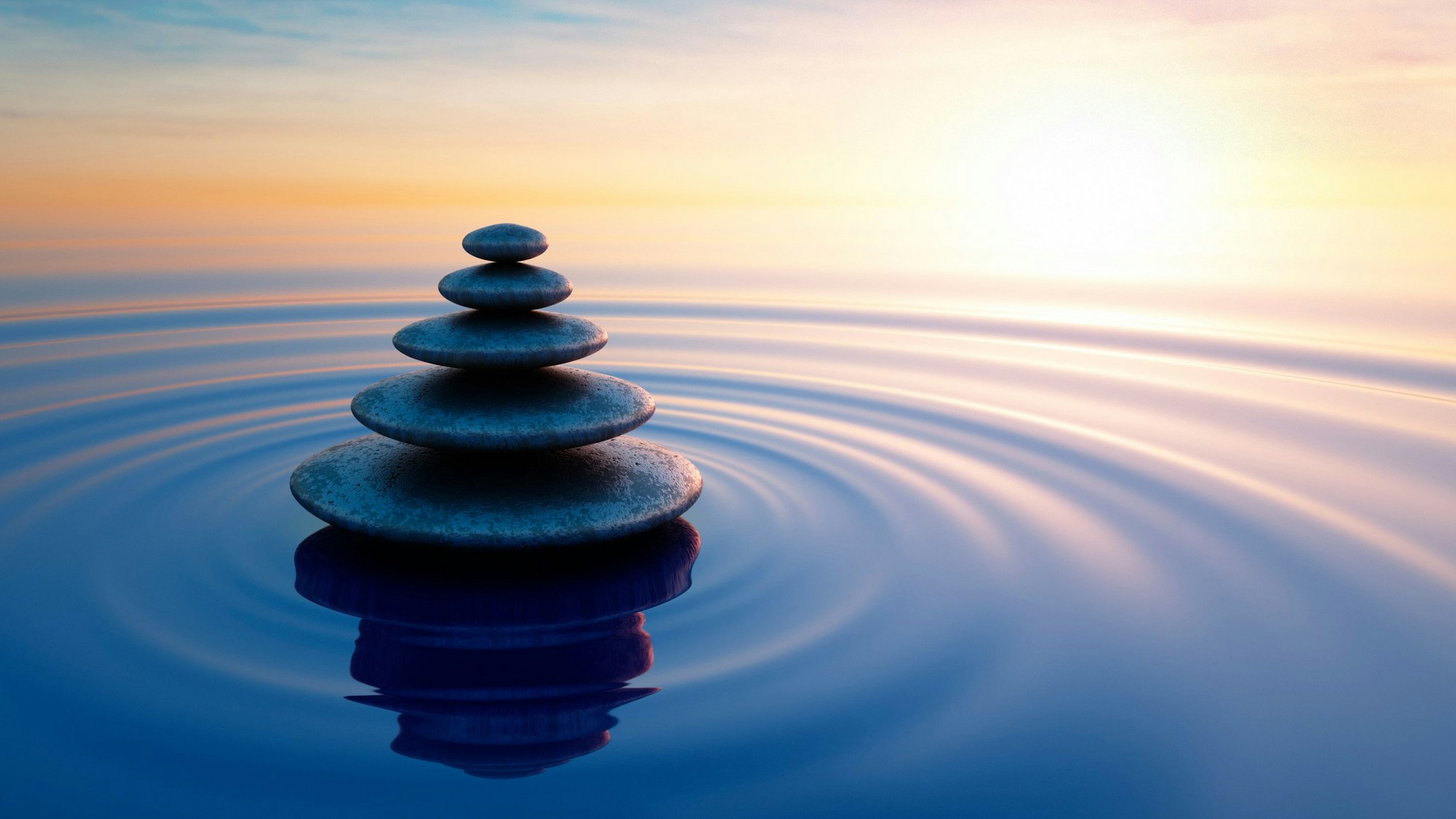 Ein Steinstapel in ruhigem Meer, Abendsonne am Horizont