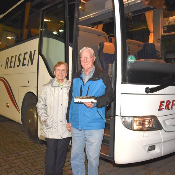 Eine Frau und ein Mann stehen vor einem weißen Reisebus.