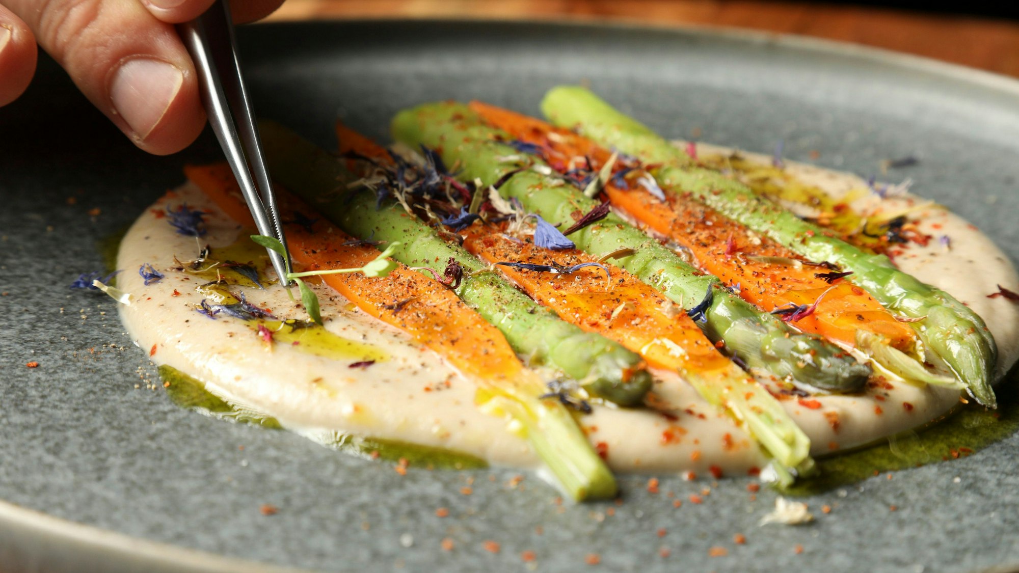 Auf dem Foto ist zu sehen, wie Simo Cordes Kräuter auf einem Gericht zurecht rückt.