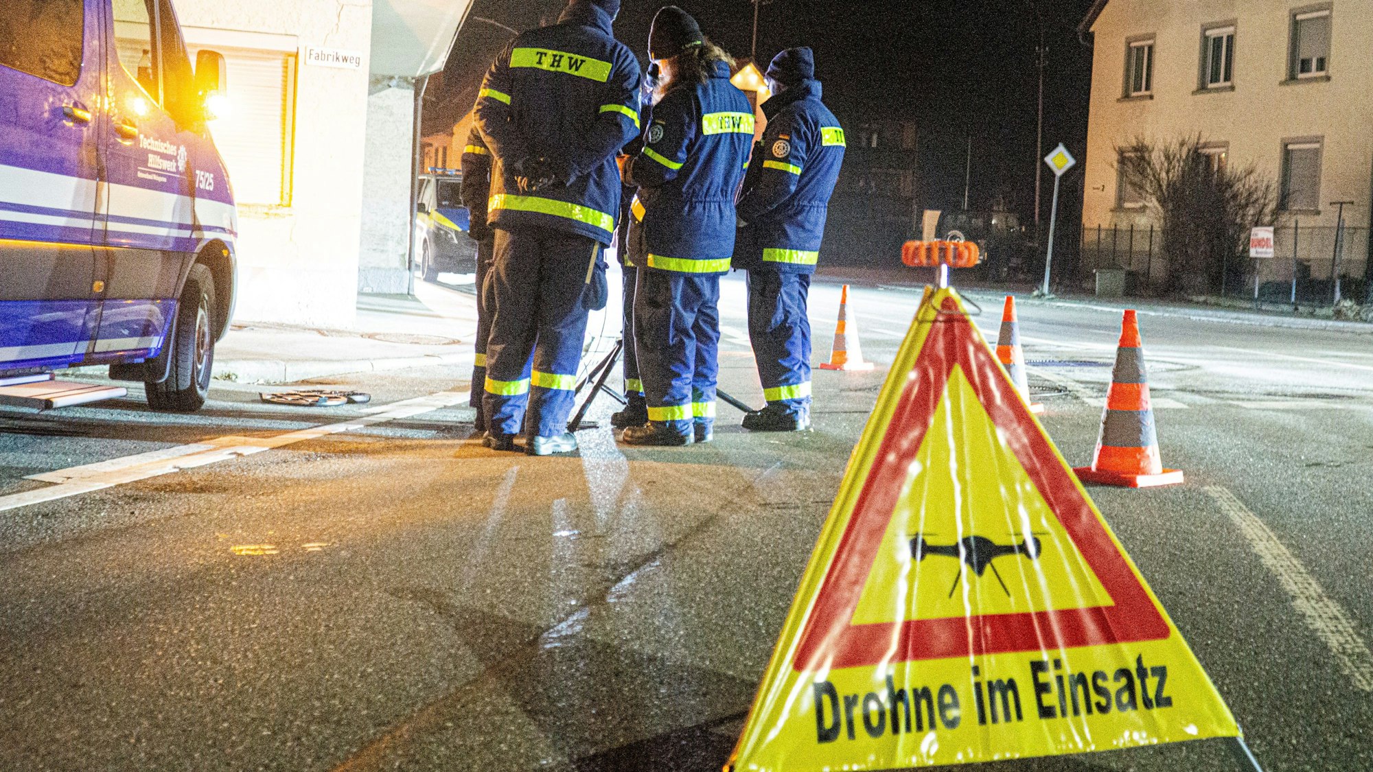 Mitglieder des THW im Einsatz. Im Vordergrund ein Warnschild „Drohne im Einsatz“.