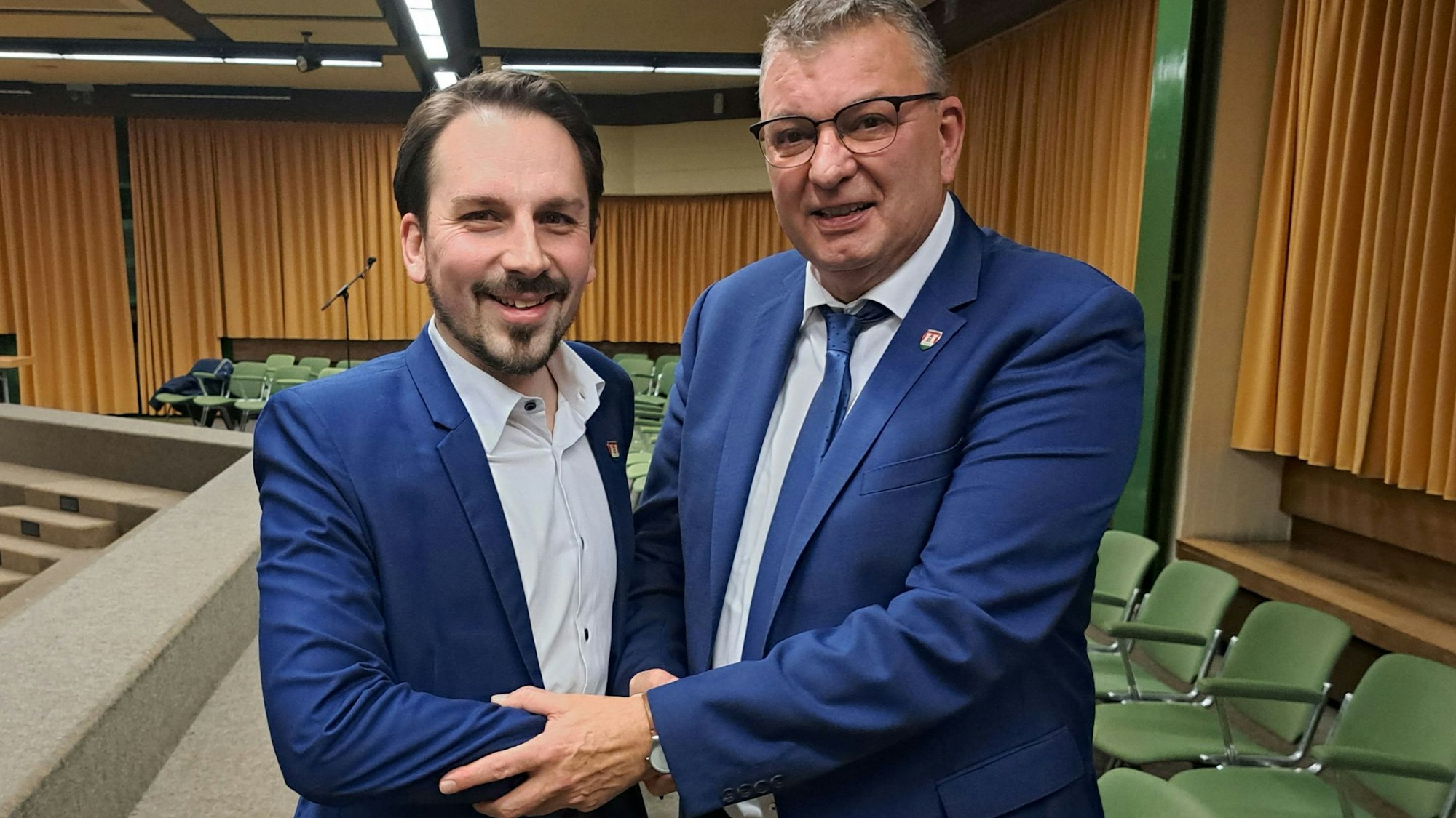 Der scheidende Niederkasseler Bürgermeister Stephan Vehreschild (rechts) und sein Nachfolger Matthias Großgarten beim Handshake nach der Ratssitzung in der Aula der Mondorfer Realschule.