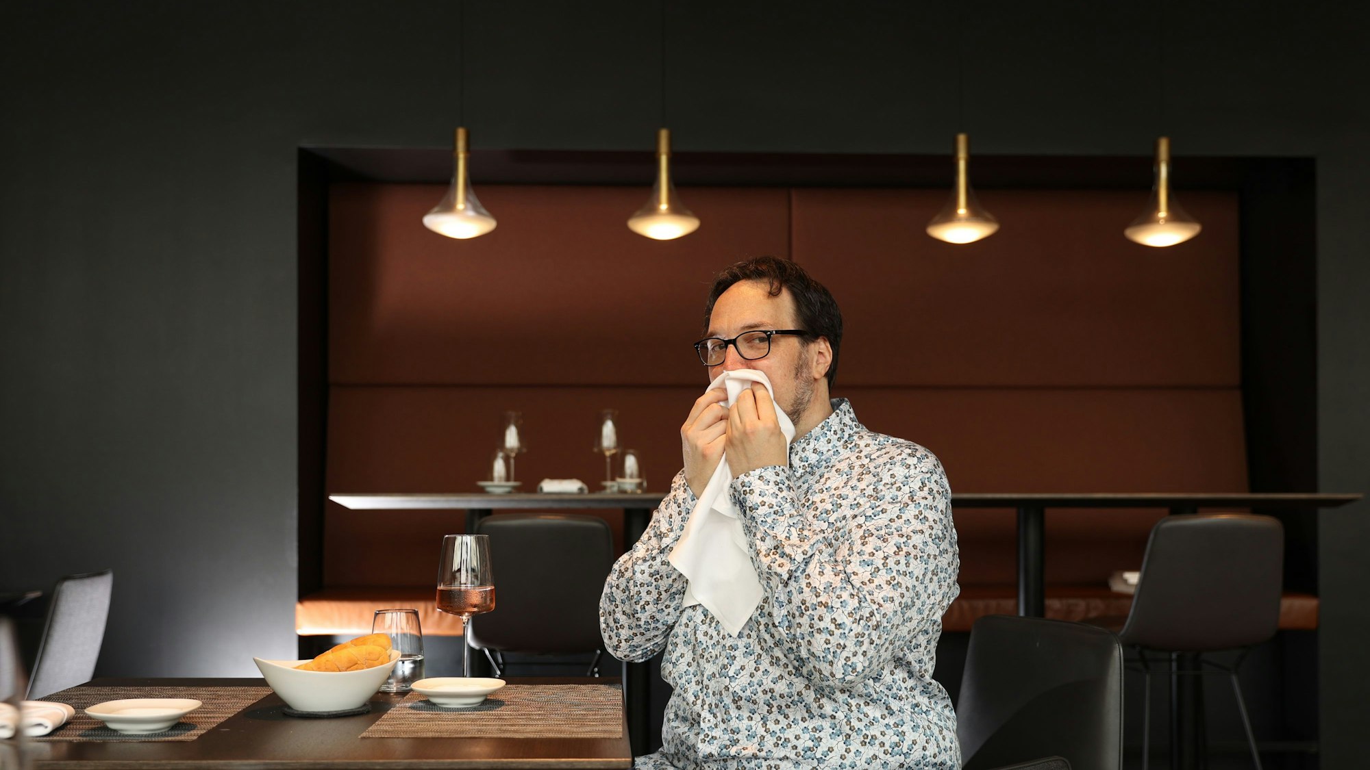 Carsten Henn sitzt am Tisch und putzt sich den Mund mit einer Serviette ab.