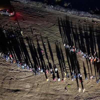 Migranten, die den Rio Grande von Mexiko aus überquert haben, stehen vor dem Aufnahmezentrum in Eagle Pass in Texas Schlange.
