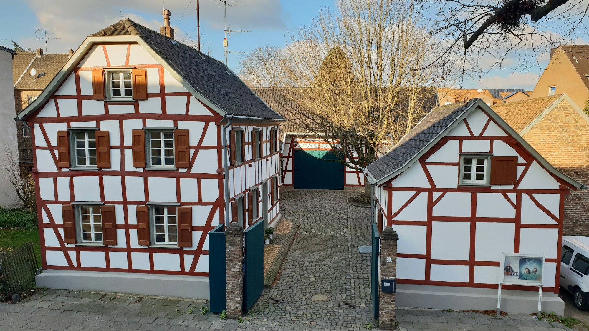 Ein Ensemble aus Fachwerkgebäuden umgibt einen Hof mit einer großen Linde.
