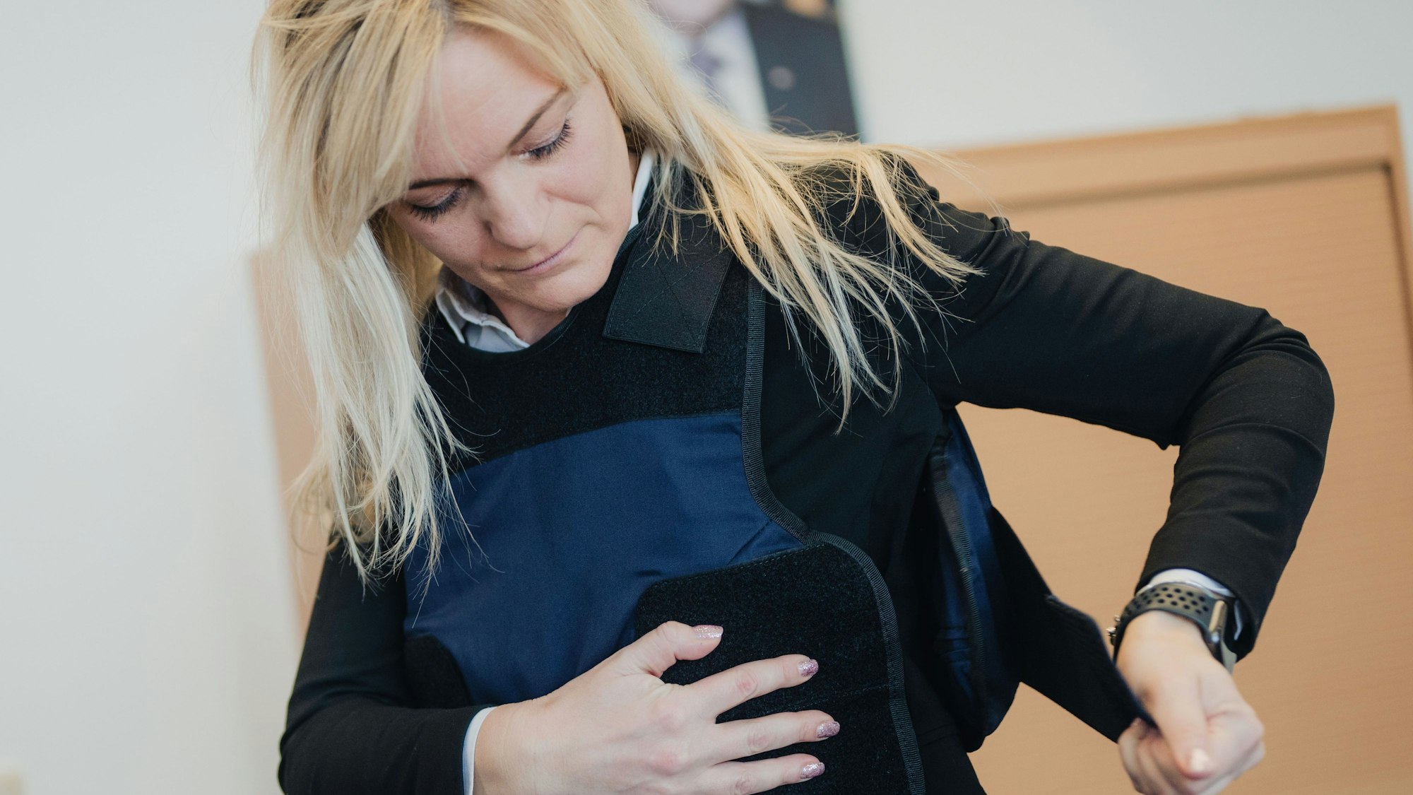 Gerichtsvollzieherin Georgia Papapostolou zieht während eines Pressetermins ihre neue Schutzweste an. Im Amtsgericht Köln wurden die ersten von landesweit 750 Schutzwesten für Gerichtsvollzieher übergeben.