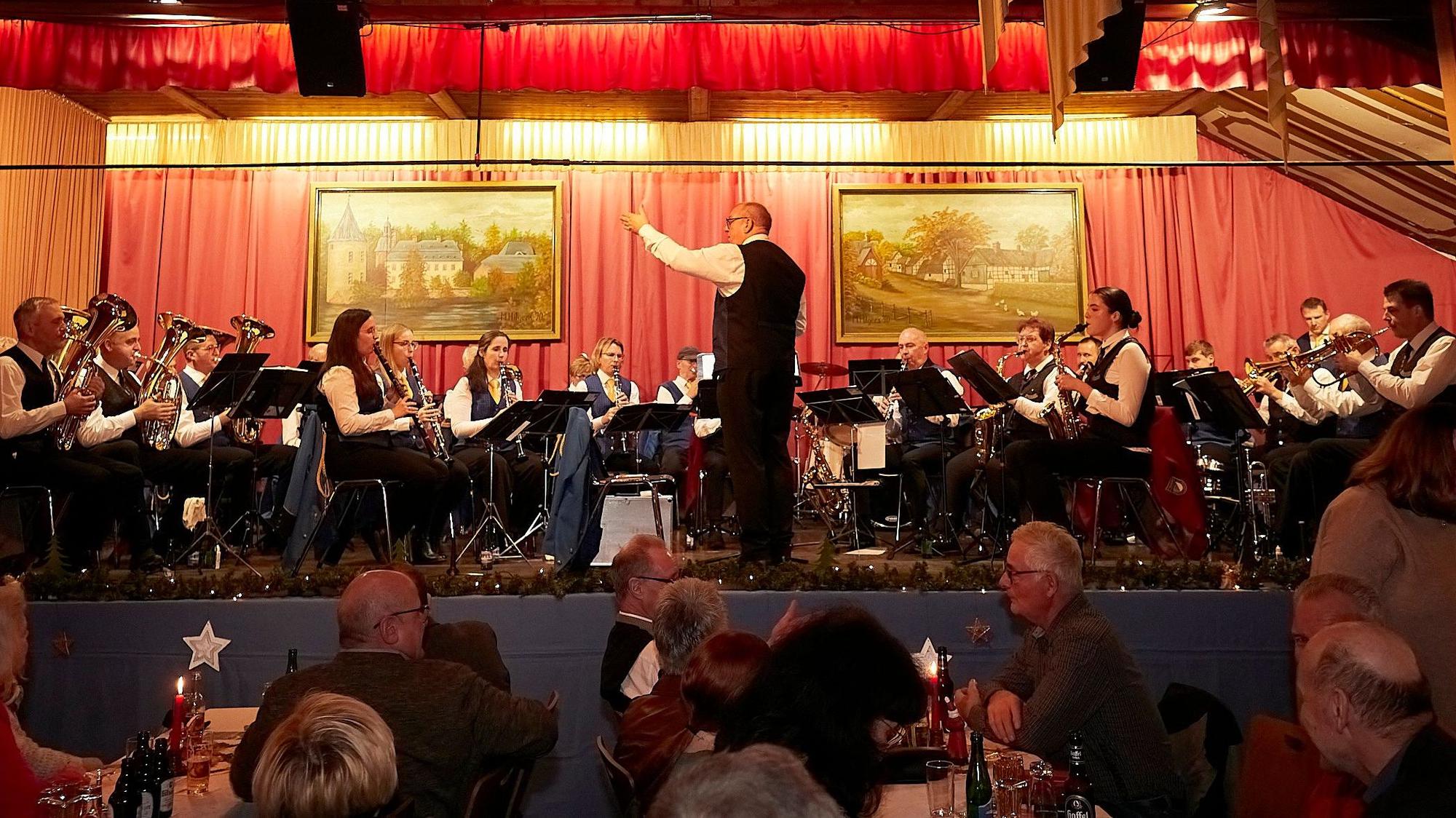 Die Musiker sitzen auf der Bühne und bedienen ihre Instrumente, Franz-Josef Strick dirigiert sie.