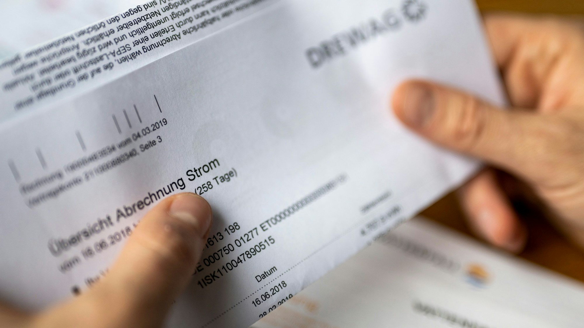 Ein Mann hält eine Stromrechnung in den Händen.