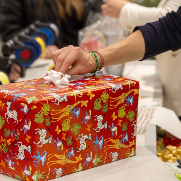 In einem Kaufhaus verpackt eine Verkäuferin für Kunden ein Weihnachtsgeschenk.
