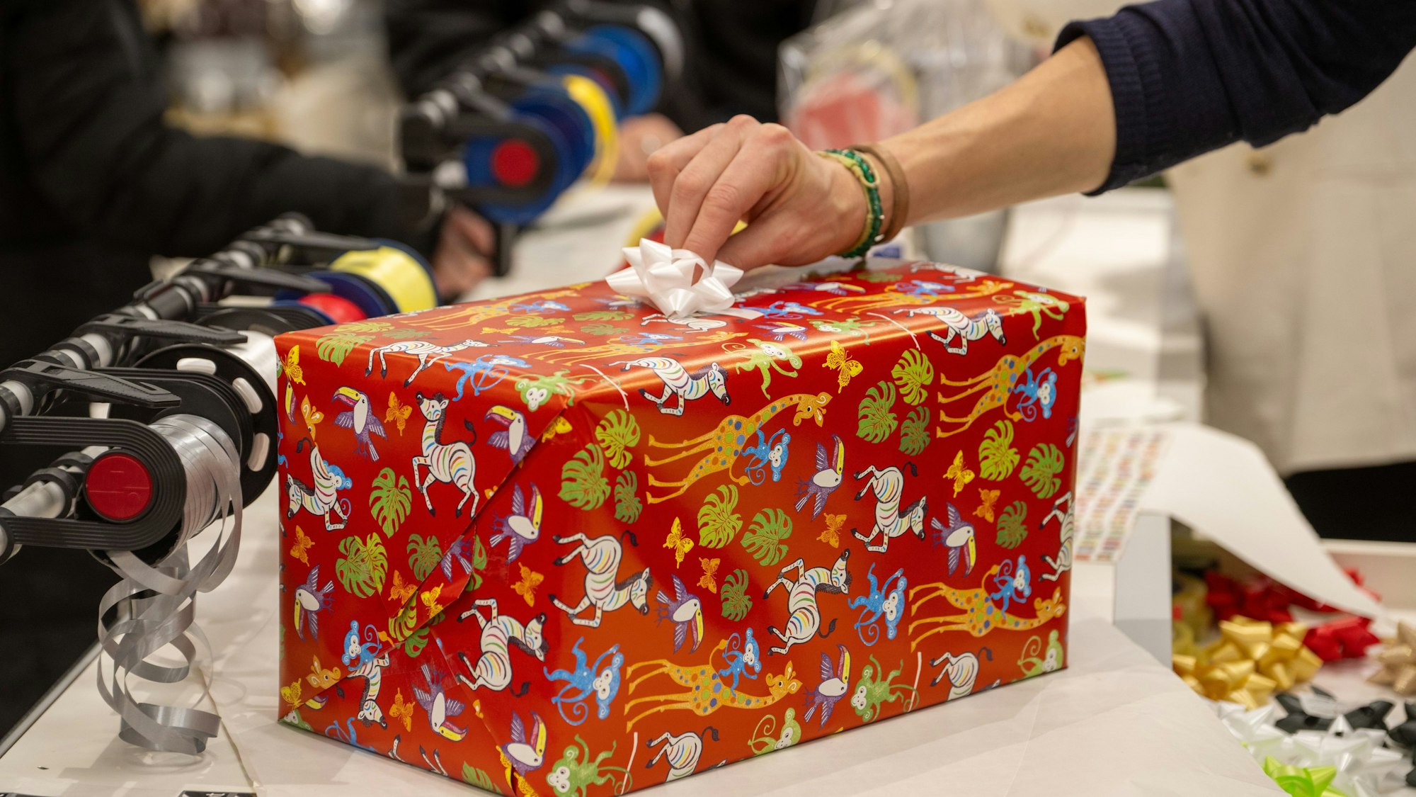 In einem Kaufhaus verpackt eine Verkäuferin für Kunden ein Weihnachtsgeschenk.