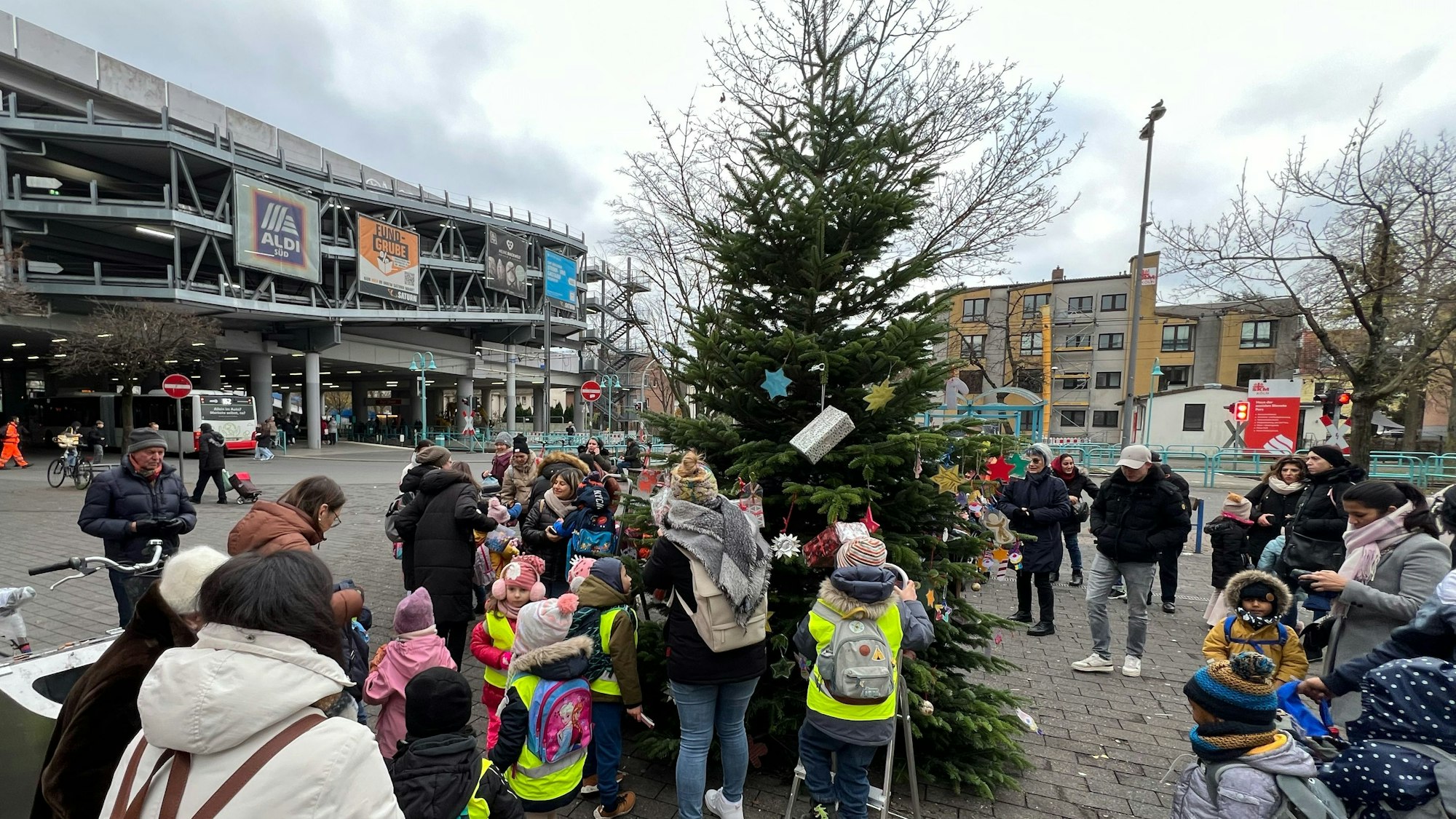 Kitakinder schmücken den Baum vor der Sparkasse in der Porzer Innenstadt.