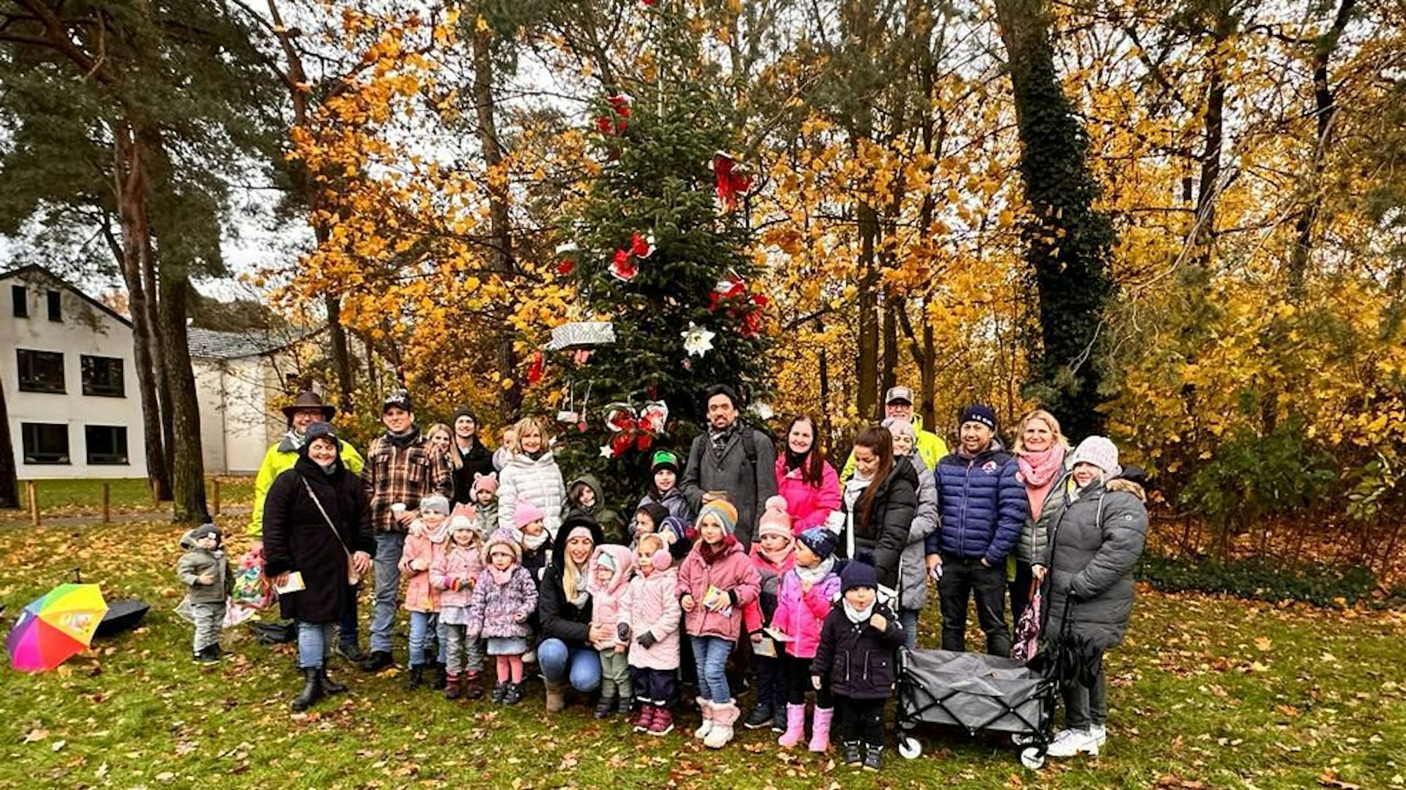Kinder stehen vor einem Baum.