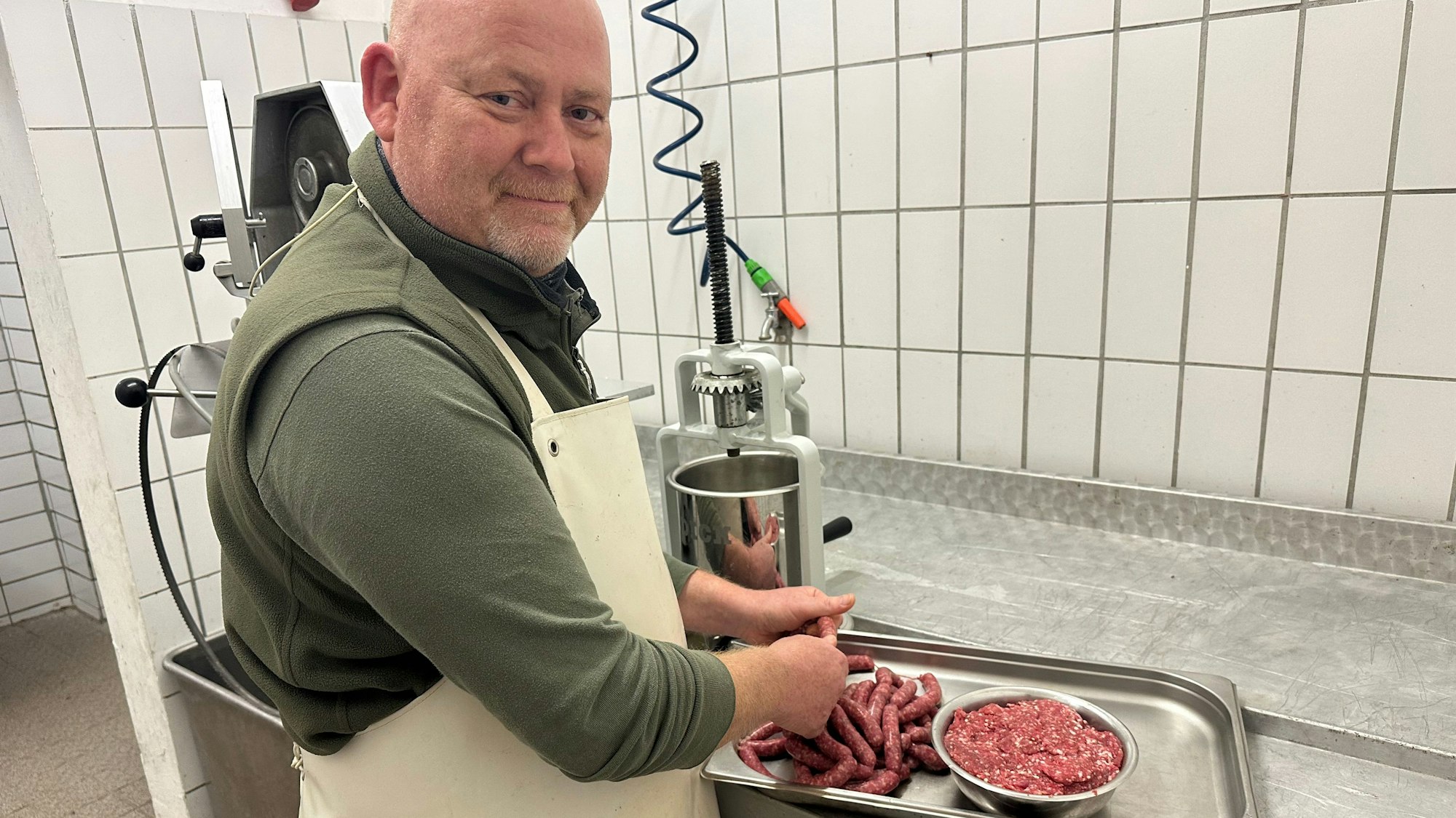 In einer weiß gefliesten Schlachtküche verarbeitet ein Jäger das Fleisch des erlegten Nutrias zu Hackfleisch und Würstchen.