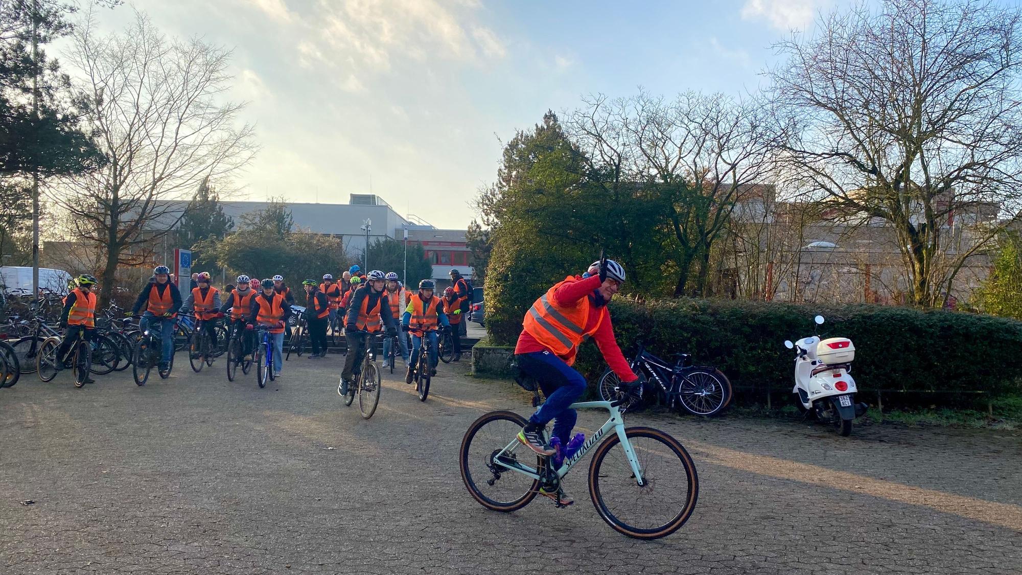 Eine Gruppe von Fahrradfahrern mit orangen Warnwesten startet vor dem Freiherr-vom-Stein Gymnasium.