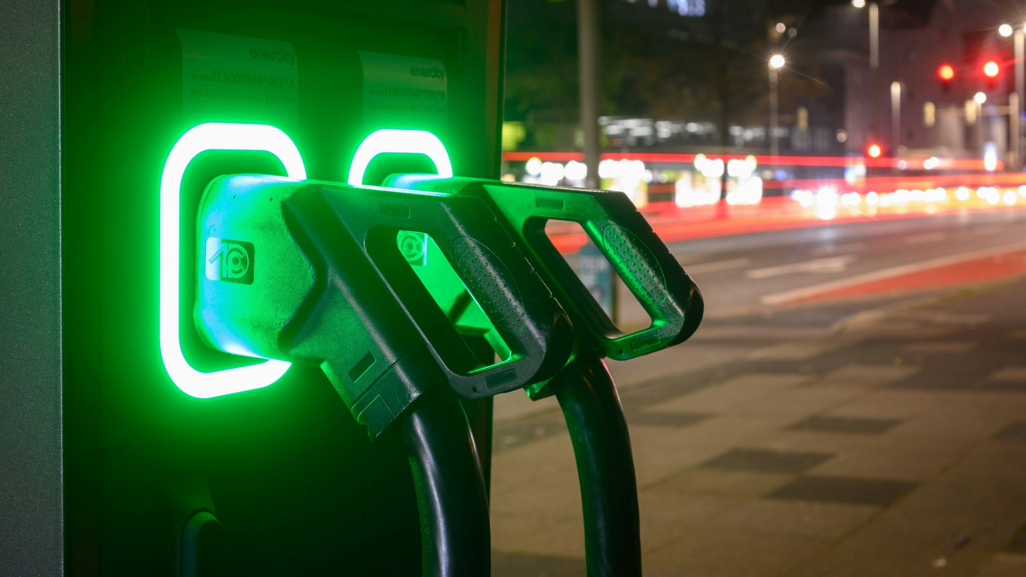 19.12.2023, Niedersachsen, Hannover: Grün leuchten Ladekabel an einer Schnellladesäule für Elektroautos. Nach dem plötzlichen Ende der Kaufprämie für Elektroautos schauen Kunden nun in die Röhre. Die Industrie protestiert und beklagt einen Vertrauensverlust in die Politik. Als Teil ihres Sparprogramms vereinbarten die Koalitionsspitzen der Ampel von SPD, Grünen und FDP vor wenigen Tagen, die staatliche Förderung «zeitnah» auslaufen zu lassen. Foto: Julian Stratenschulte/dpa +++ dpa-Bildfunk +++