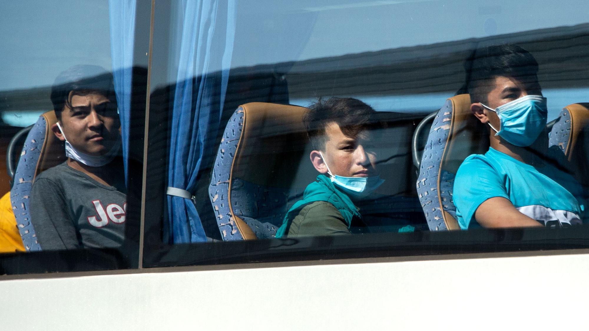 Junge Flüchtlinge, teilweise mit Mundschutz, sitzen in einem Bus am Flughafen Hannover.