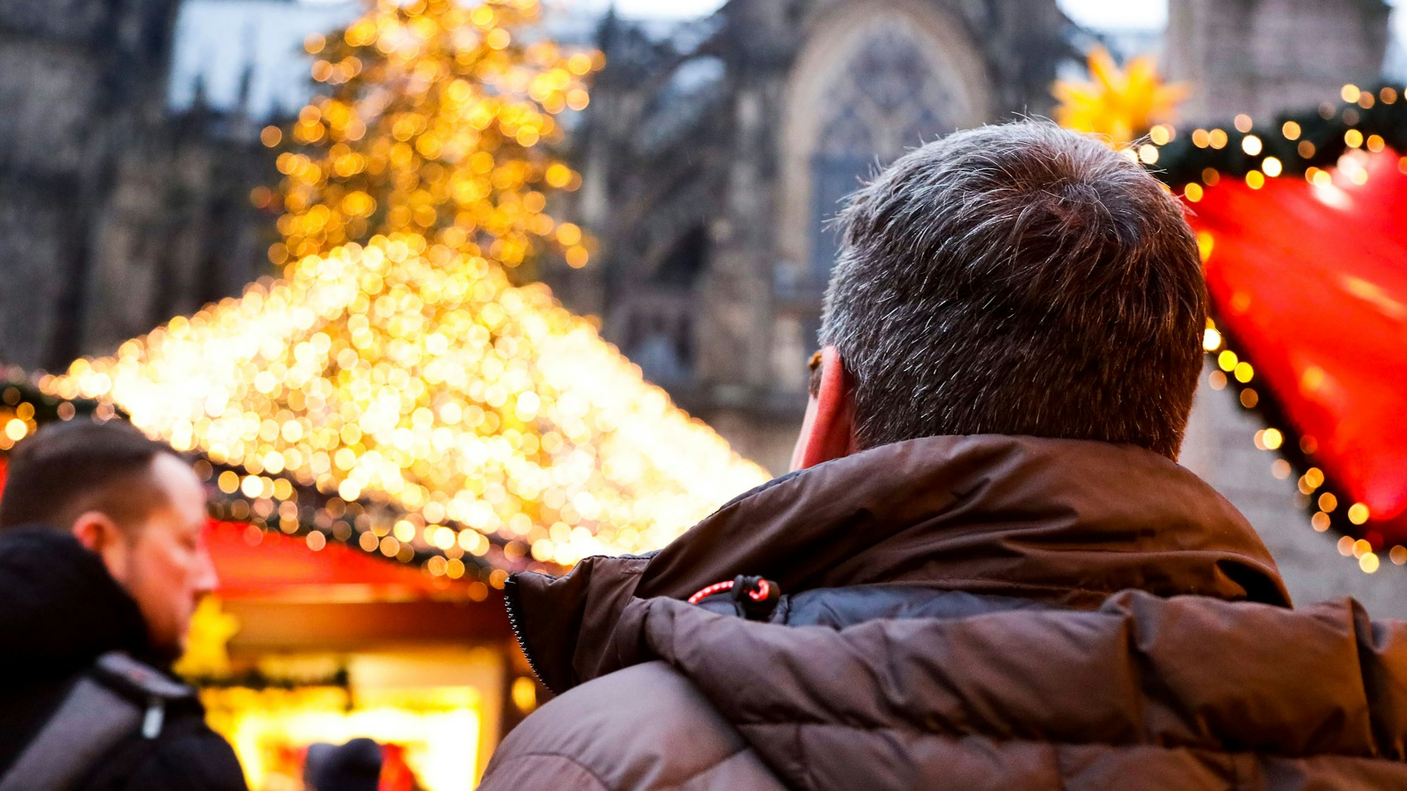 Ein Mann steht auf dem Weihnachtsmarkt am Kölner Dom