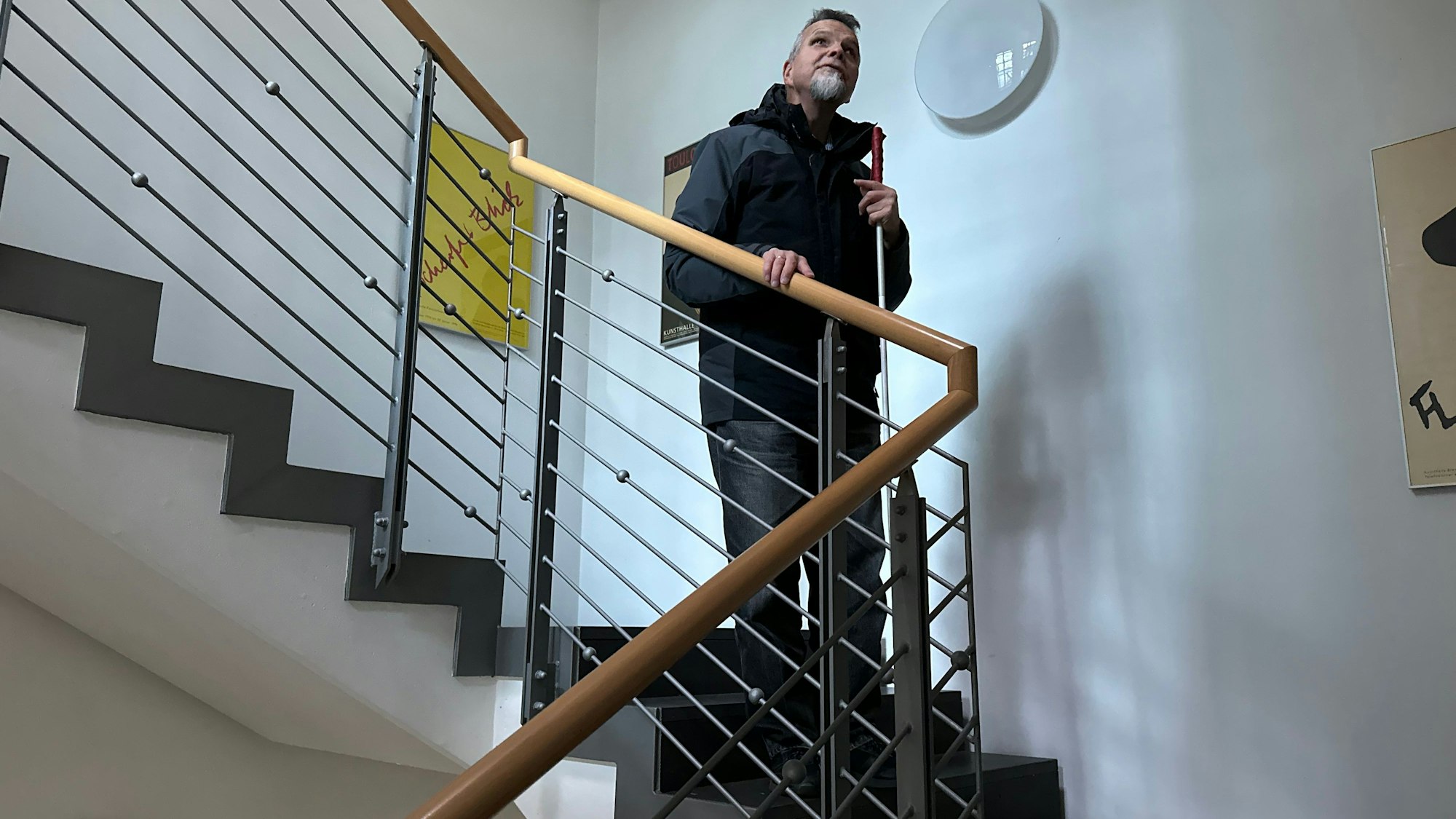 Günther Heger greift an ein Treppengeländer, so fühlt er wie es auf und ab geht.