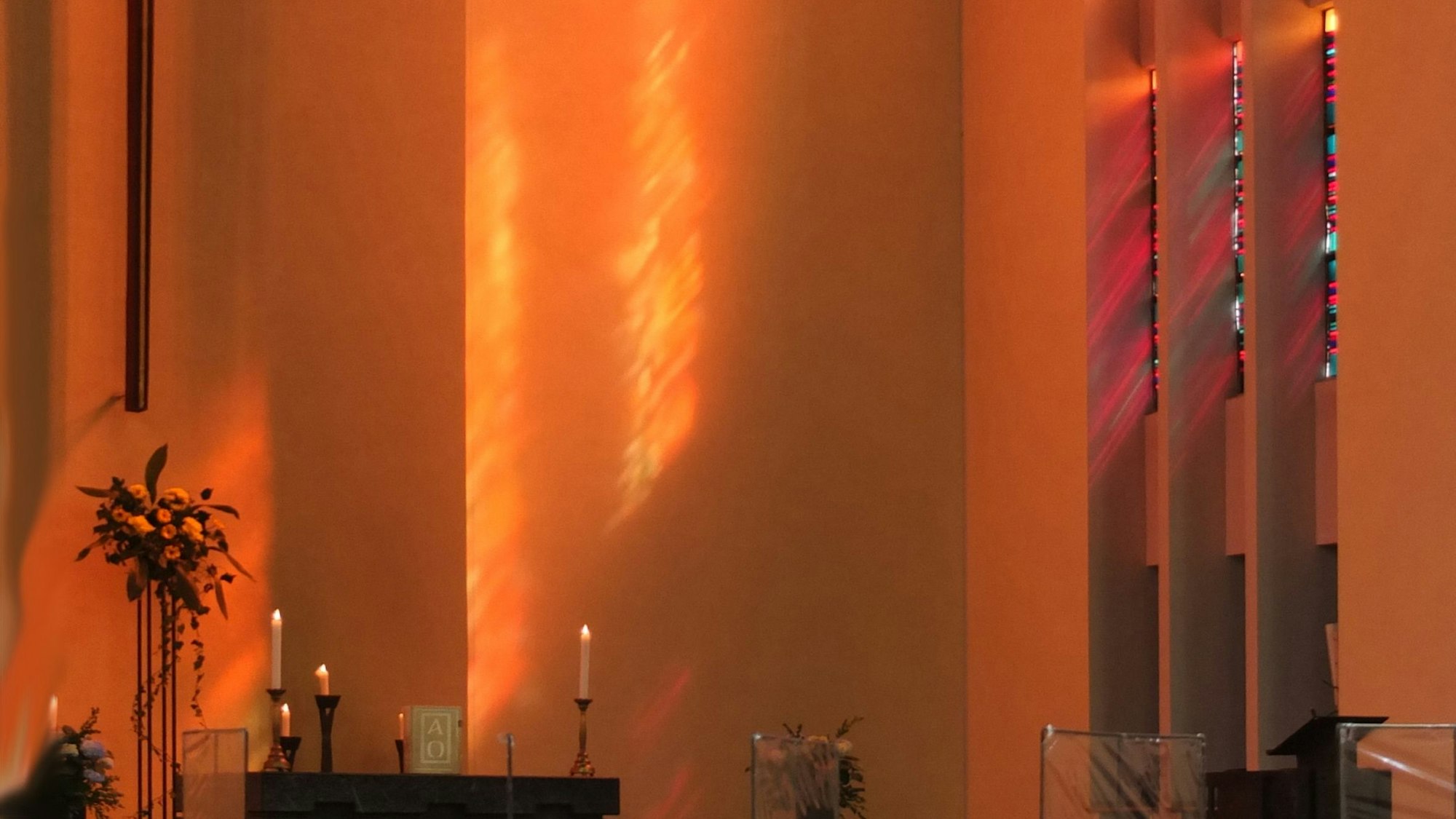 Der Altarraum einer ist in rötliches Licht getaucht.