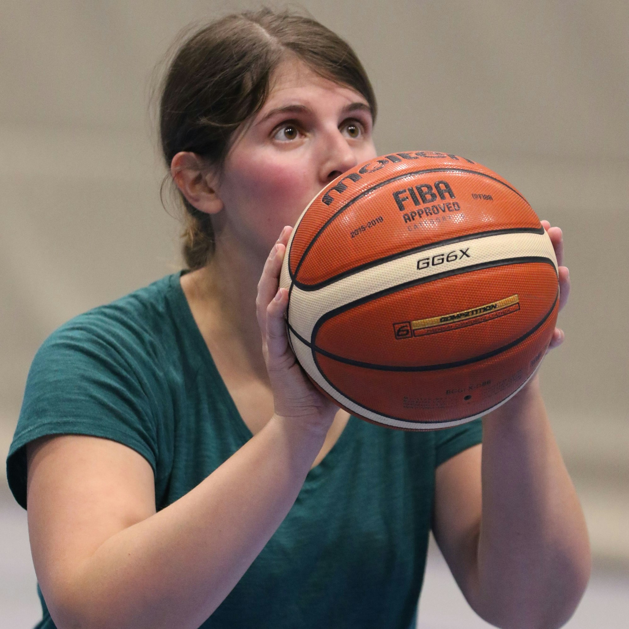 Julia Reuß hält einen Basketball in den Händen und schaut konzentriert nach oben.