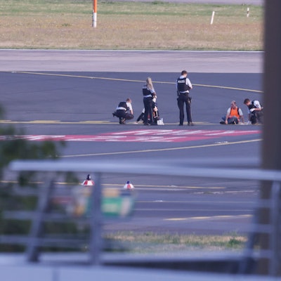 Polizistinnen und Polizisten stehen neben Mitgliedern der Klima-Gruppe Letzte Generation, die sich im Juli 2023 auf dem Rollfeld am Düsseldorfer Flughafen festgeklebt haben.
