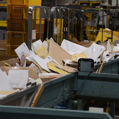 Große Mengen Post auf einem Förderband, das fast überquillt.